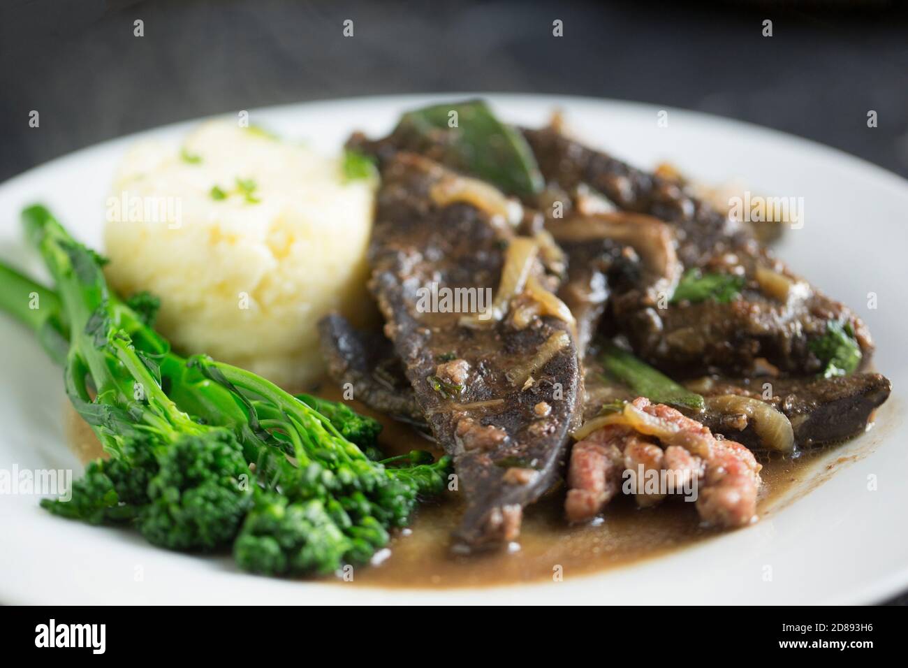 Fette di fegato cotto da un capriolo che sono state cucinate con pancetta, funghi, cipolle, brodo di manzo, salvia e prezzemolo. Servito con purè di patate Foto Stock