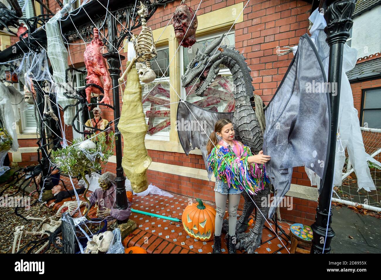 Rosie Hargreaves, 10 anni, controlla le ali di un enorme drago nella sua casa di famiglia a Llandaff, vicino a Cardiff, che è decorato e adornato con decine di decorazioni realistiche di Halloween, installato da suo padre, Danny Hargreaves, che lavora in TV effetti speciali. Foto Stock