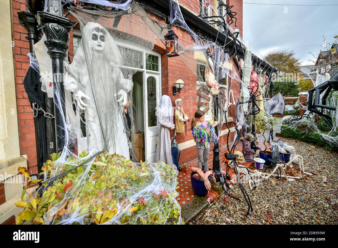 Rosie Hargreaves, 10, mette le reti dei ragni falsi su un ghouls e sui mostri alla sua casa di famiglia in Llandaff, vicino Cardiff, che è decked fuori e adornato con i punteggi delle decorazioni realistiche di Halloween osservanti, installate dal suo padre, Danny Hargreaves, che lavora in effetti speciali della TV. Foto Stock