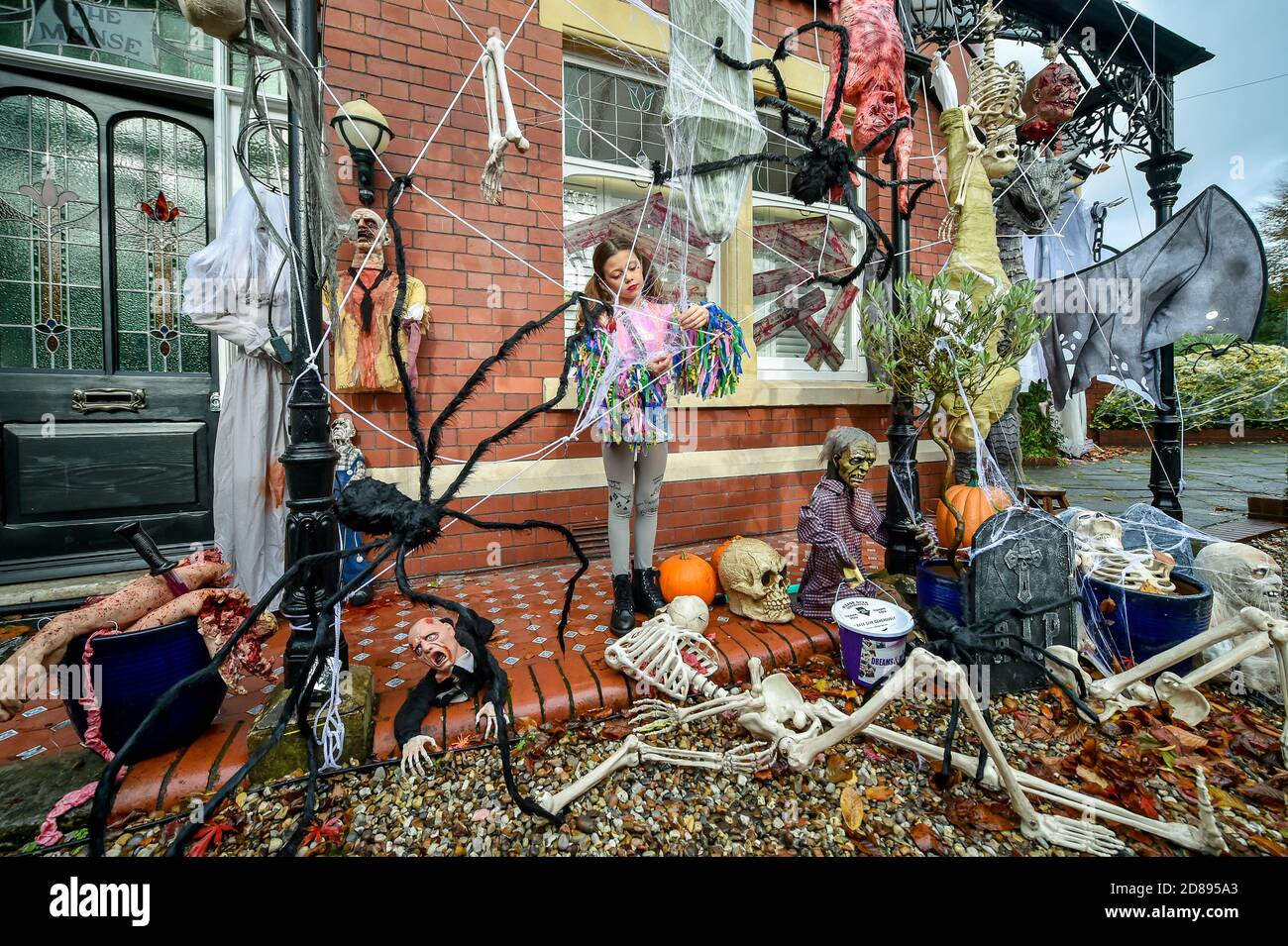Rosie Hargreaves, 10, mette le reti dei ragni falsi su un ghouls e sui mostri alla sua casa di famiglia in Llandaff, vicino Cardiff, che è decked fuori e adornato con i punteggi delle decorazioni realistiche di Halloween osservanti, installate dal suo padre, Danny Hargreaves, che lavora in effetti speciali della TV. Foto Stock