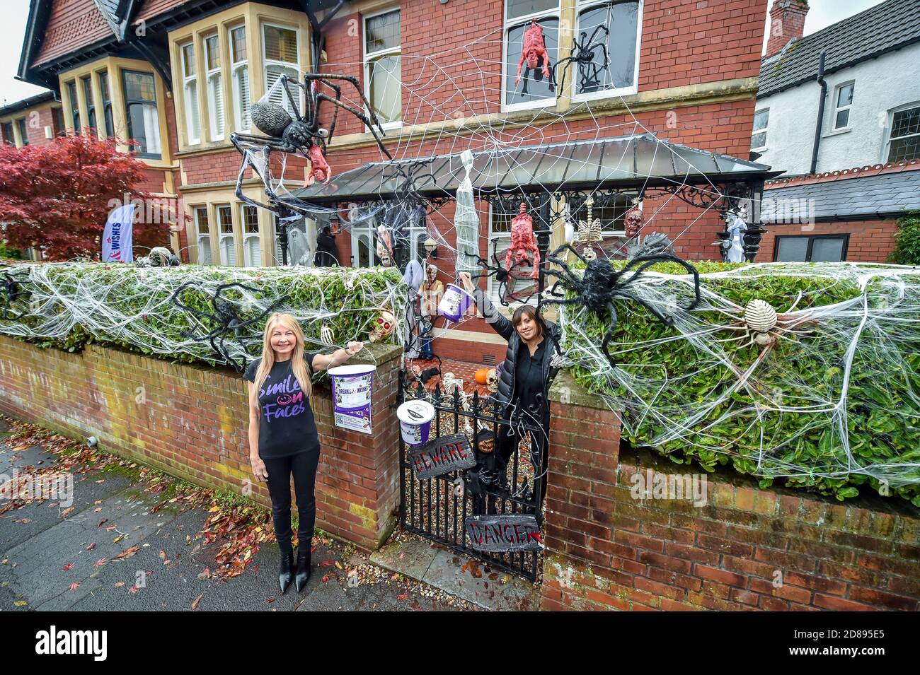 Wendy Hobbs da Dreams & Wishes beneficenza, sinistra, e Carmela Hargreaves tenere caritatevoli collezioni secchi a casa di famiglia Carmela a Llandaff, vicino a Cardiff, che è decked fuori e adornato con decine di decorazioni realistiche di Halloween, installato dal marito Danny Hargreaves, Che lavora in TV effetti speciali, come stanno raccogliendo denaro per la carità attraverso la donazione pubblica. Foto Stock