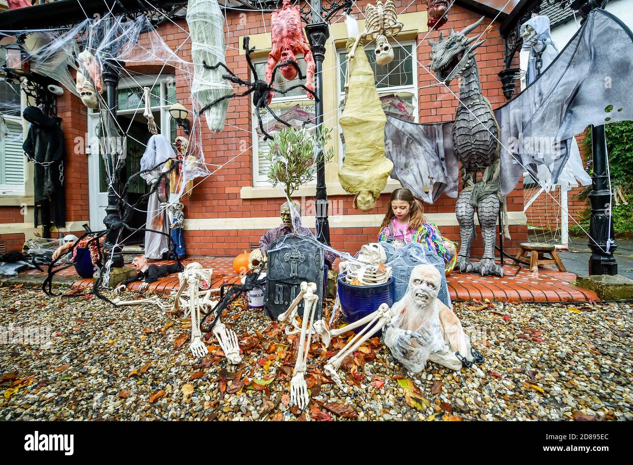 Rosie Hargreaves, 10, mette le reti dei ragni falsi su un lapide alla sua casa di famiglia in Llandaff, vicino Cardiff, che è decked fuori e adornato con le partiture realistiche che osservano Halloween, installato da suo padre, Danny Hargreaves, che lavora in TV effetti speciali. Foto Stock
