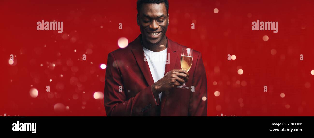 Ragazzo rilassato con un bicchiere di champagne e pensando a Natale. Uomo che ricorda un momento speciale mentre ha un bicchiere di Champ Foto Stock