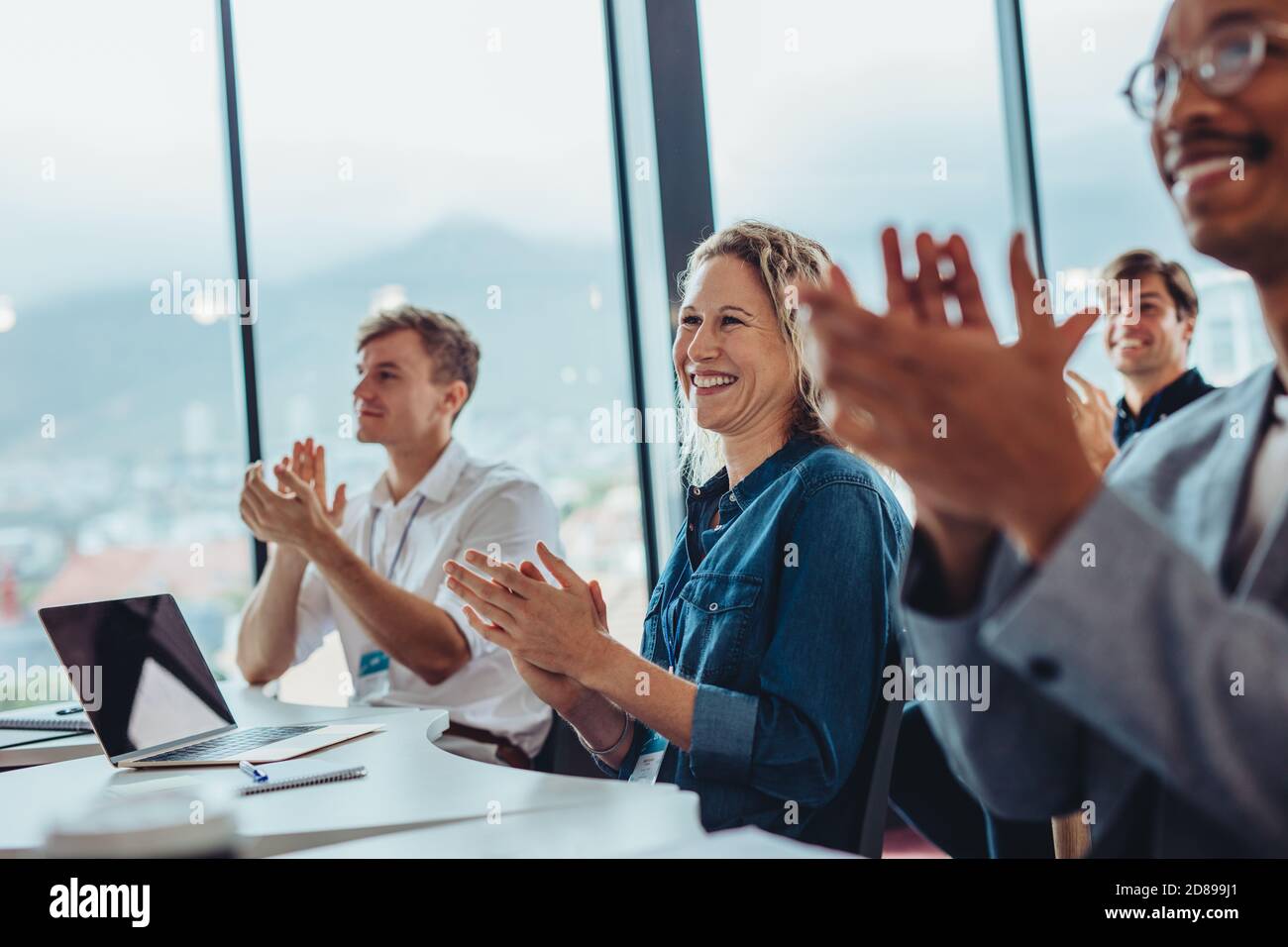 Gruppo di professionisti del business maschili e femminili che si aggrappano le mani in conferenza. Il pubblico applaude dopo il seminario di successo. Foto Stock