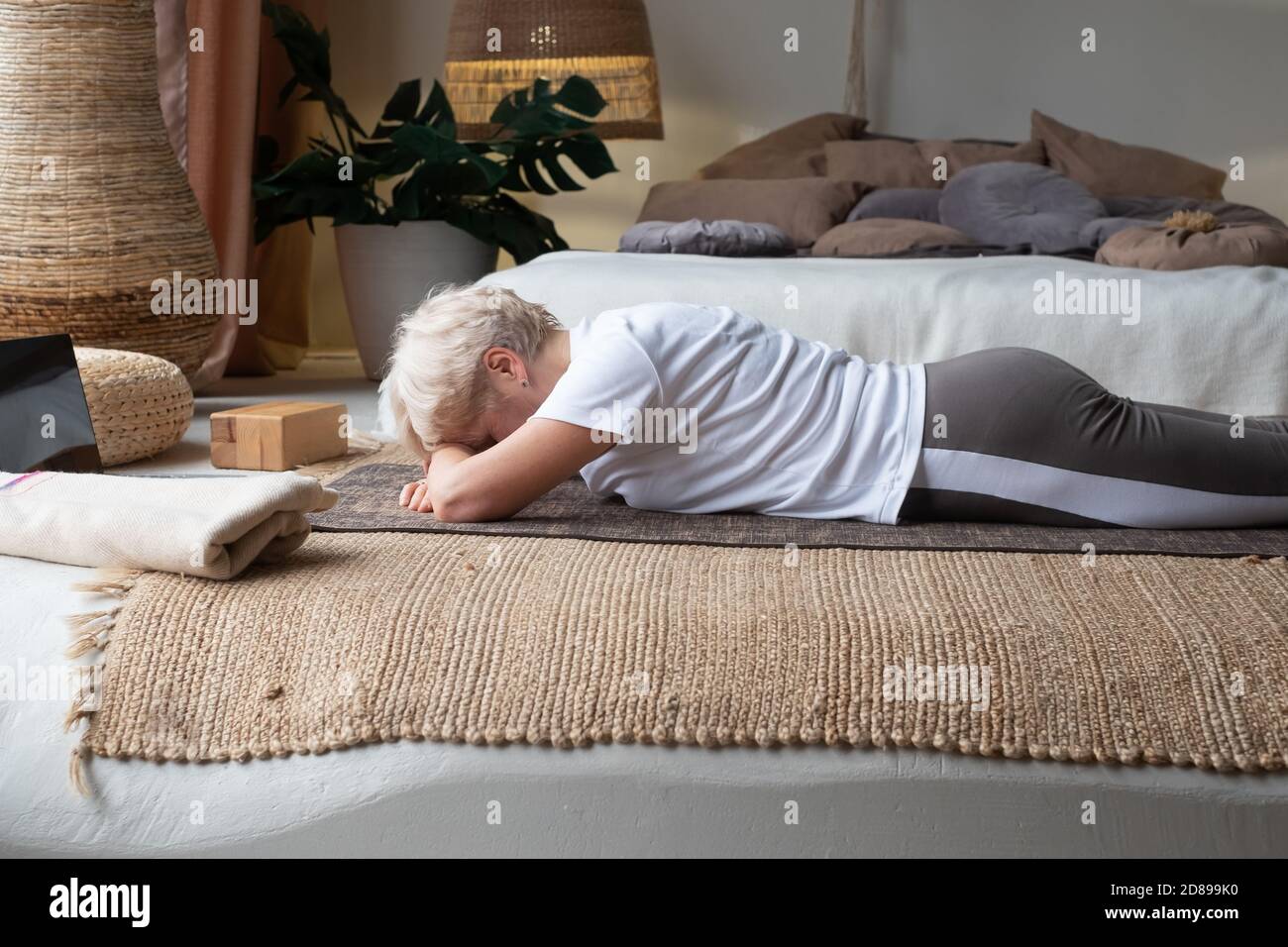 Donna anziana si rilassa in yoga asana Makarasana o coccodrillo posa Foto Stock