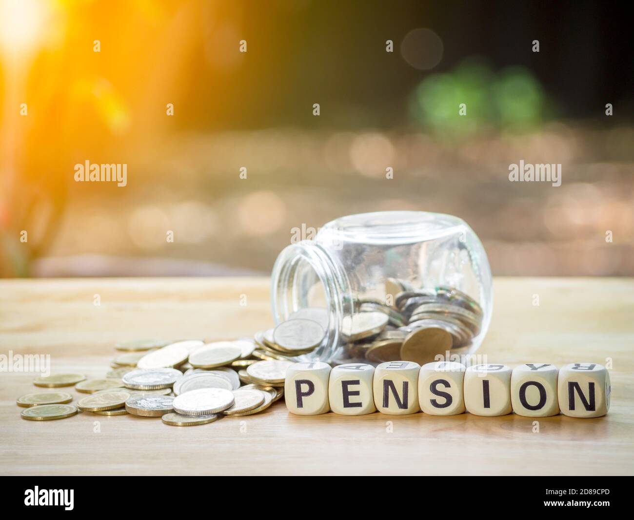 Monete in barattolo con blocco di legno scritto testo PENSIONE su tavola di legno a risparmio di denaro per previdenza finanziaria e assicurazione rendita. Concetto per Foto Stock