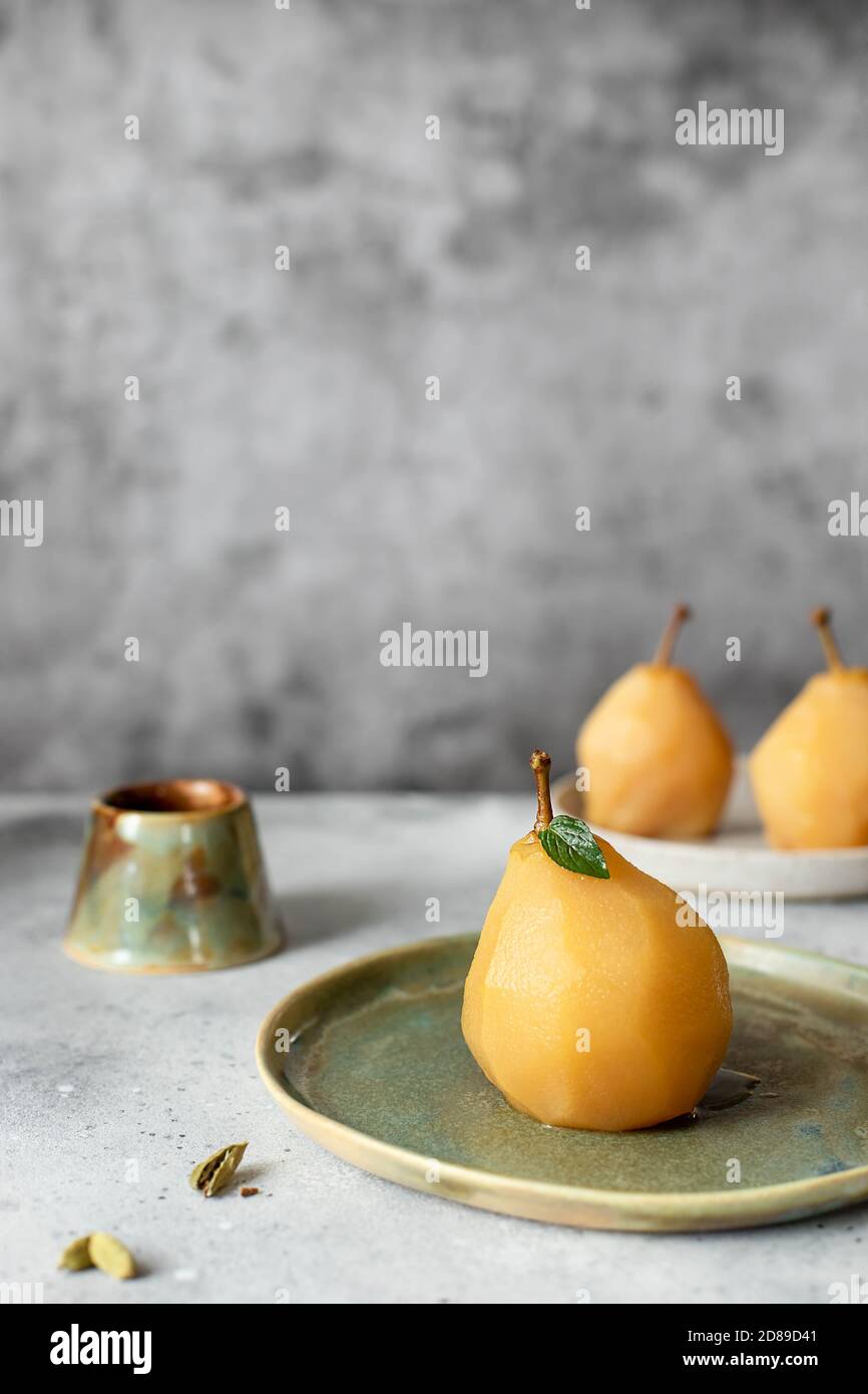 Deliziosa pera d'oro in camicia con cannella e cardamomo. Sfondo grigio. Foto Stock