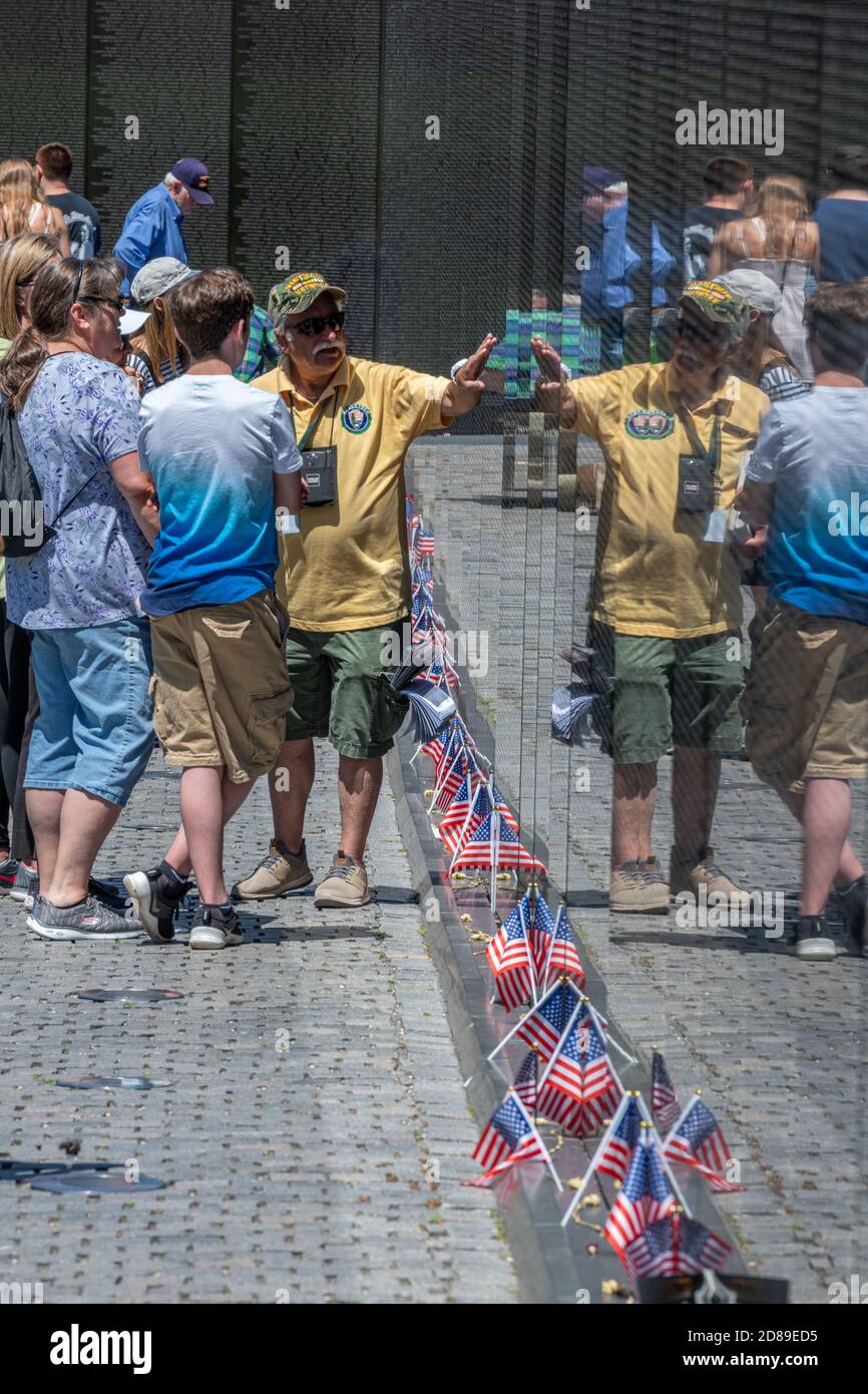 Amici e parenti cercano sul granito nero lucido del Vietnam Veterans Memorial per i nomi dei cari persi nella guerra. Foto Stock