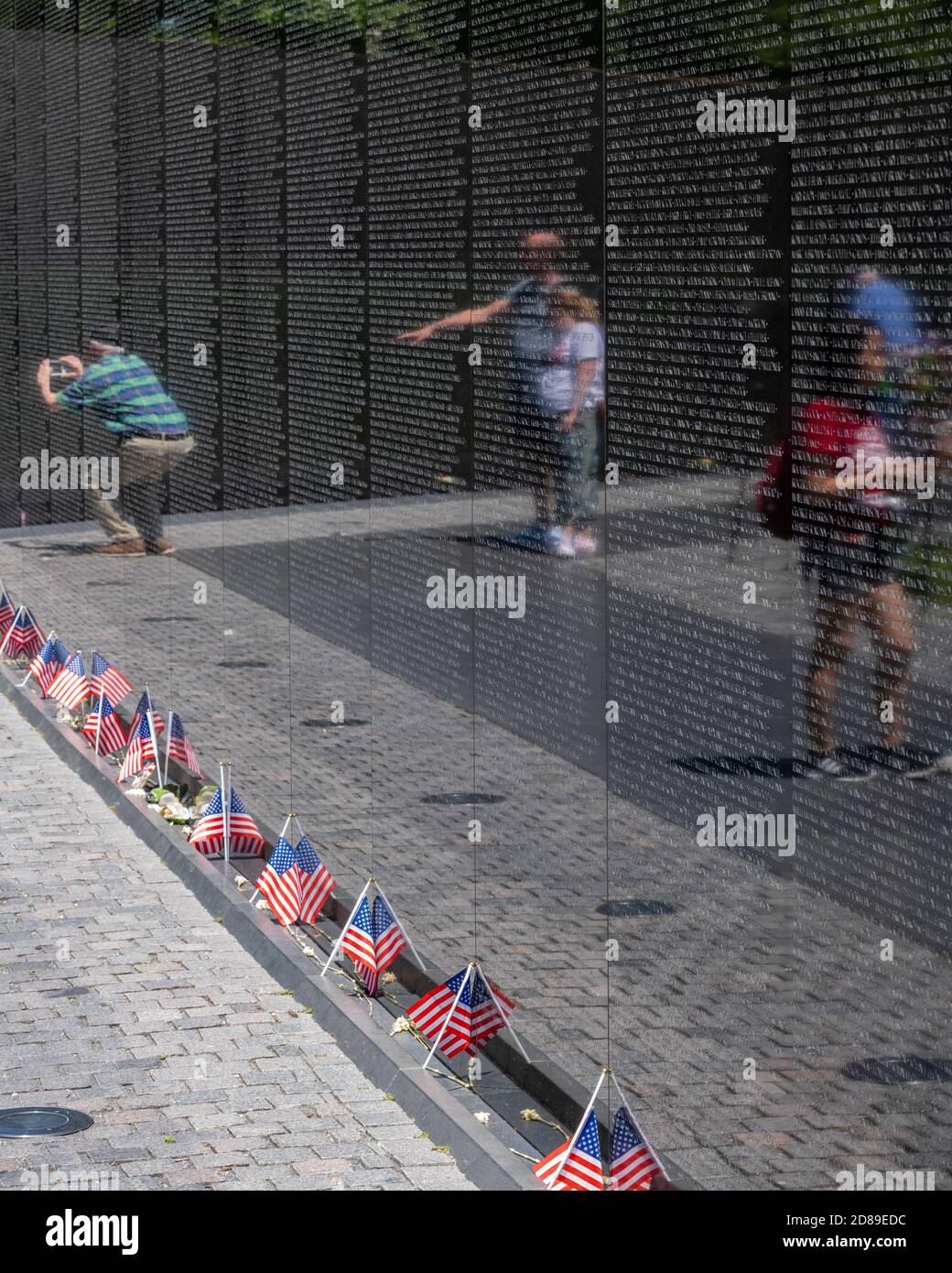Amici e parenti cercano sul granito nero lucido del Vietnam Veterans Memorial per i nomi dei cari persi nella guerra. Foto Stock