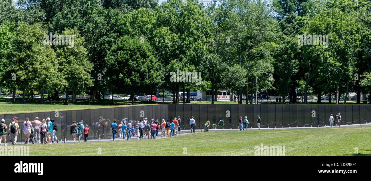 Amici e parenti cercano sulle pareti di granito nero lucido del Vietnam Veterans Memorial per i nomi dei cari persi nella guerra. Foto Stock