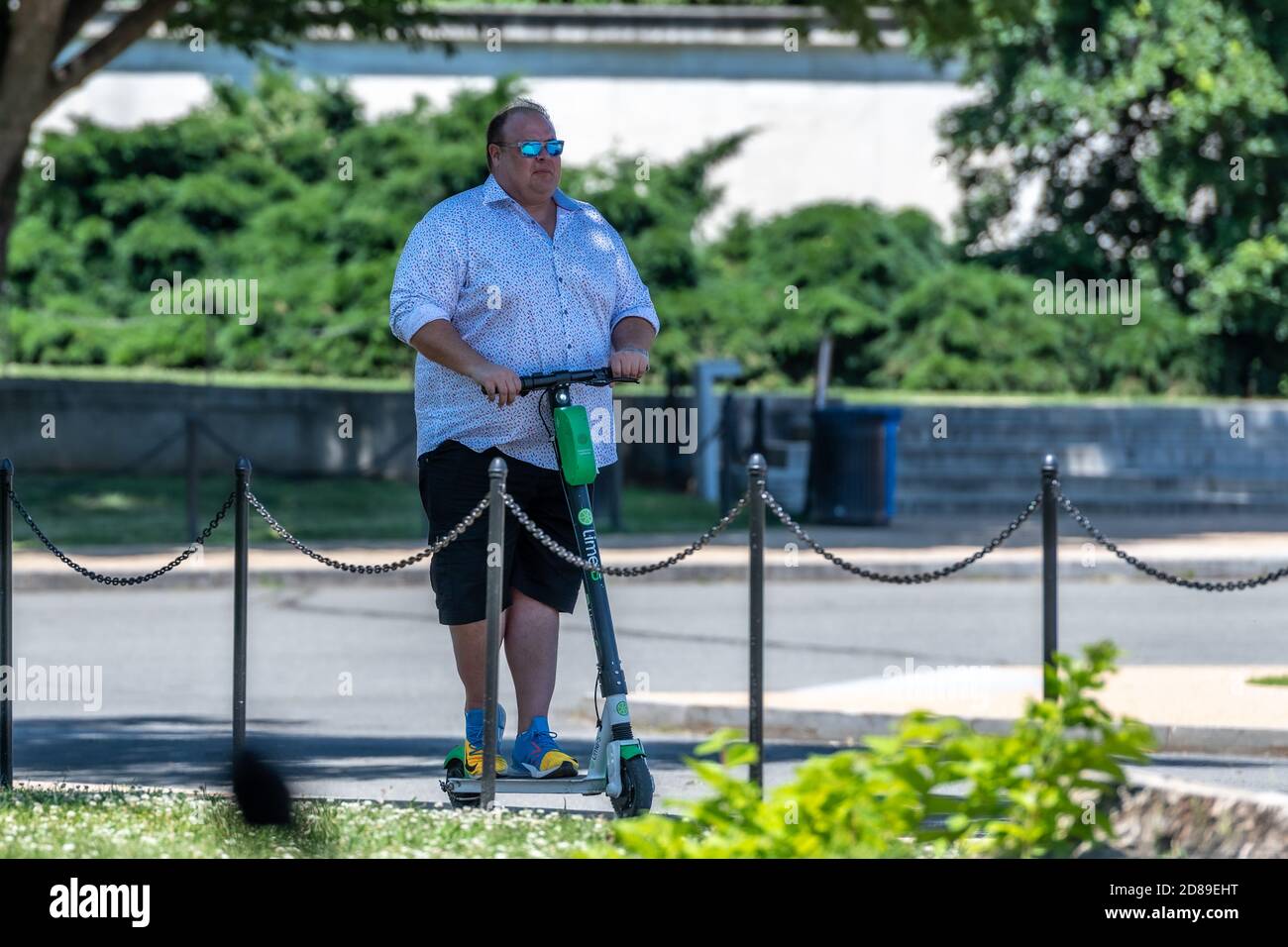 Un uomo di grandi dimensioni che guida uno scooter elettrico Lime-S sulla East Basin Drive SW a Washington DC. Foto Stock