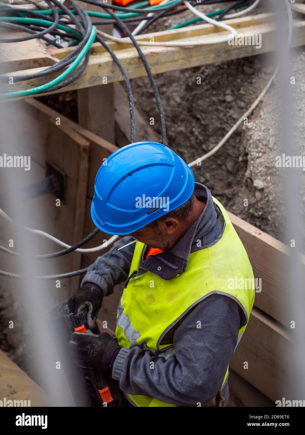 Montatore di tubi in uniforme gialla che lavora su un cantiere. Tubi di raccordo per lavoratori sotterranei, Ginevra, Svizzera. Foto Stock