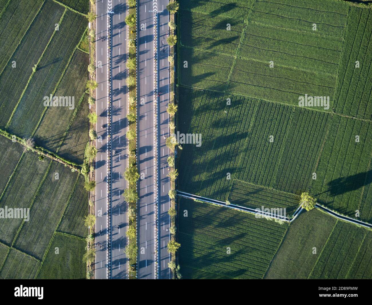 Vista aerea dei ciclisti su una strada attraverso il paesaggio rurale, Mataram città, Lombok, Indonesia Foto Stock