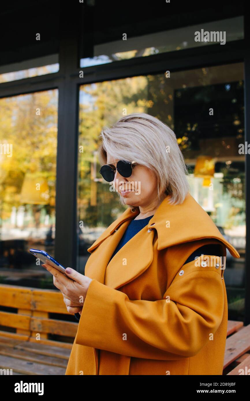 Ritratto di una donna matura in piedi per strada guardando il suo cellulare, la Russia Foto Stock