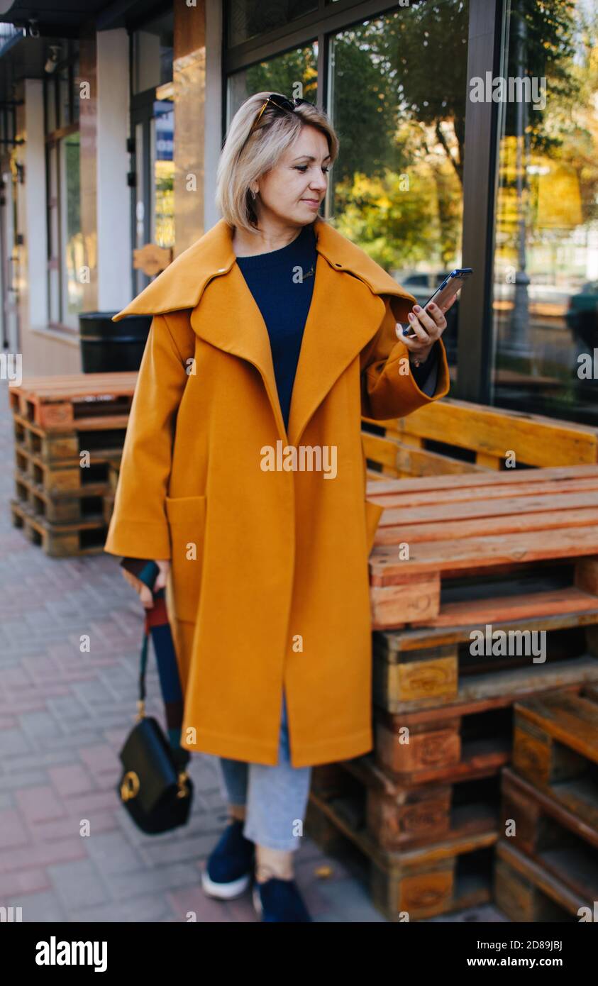 Donna sorridente in piedi per strada guardando il suo cellulare, Russia Foto Stock