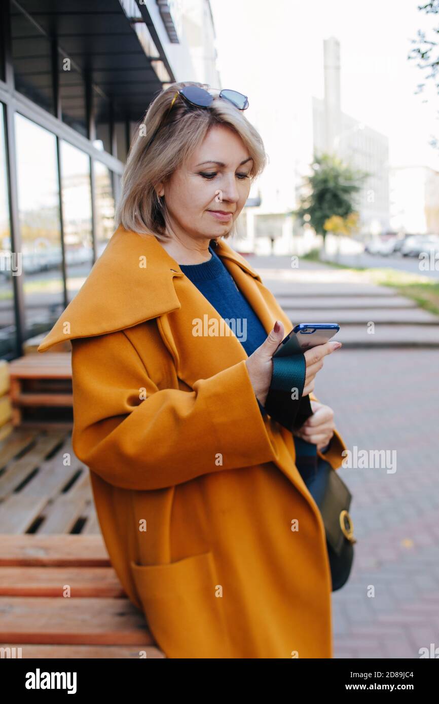 Ritratto di una donna matura in piedi per strada guardando il suo cellulare, la Russia Foto Stock