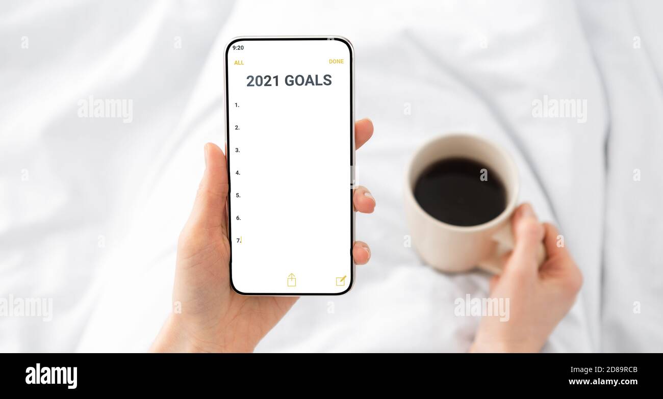 Donna Hands Holding smartphone con obiettivi per il nuovo anno 2021 Interno Foto Stock