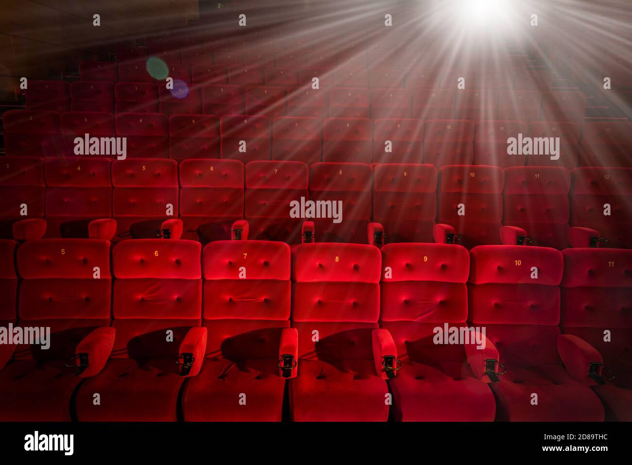 sala cinematografica con poltrone rosse e luminosa luce proiettore Foto Stock