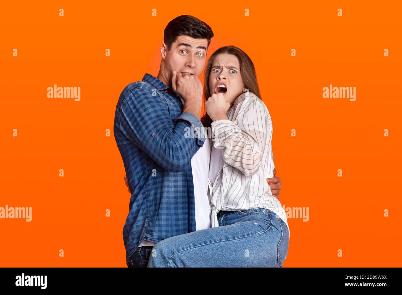Il ragazzo e la signora millennial spaventati coprono le loro bocche con le mani e guarda la fotocamera Foto Stock