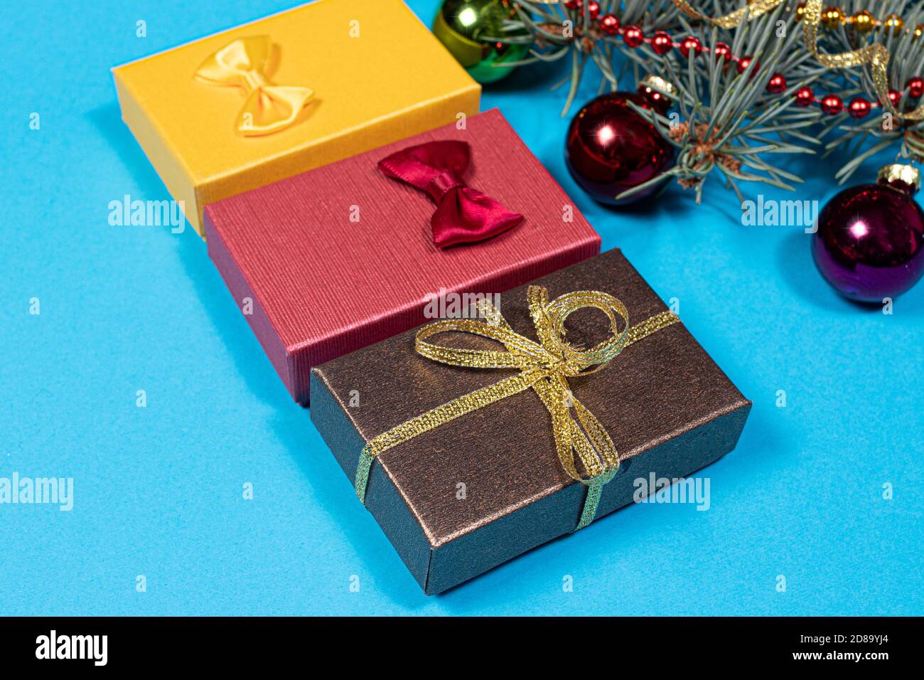 Colorati regali di Natale e ramo di abete rosso con palline su sfondo blu. Natale 2021 Foto Stock