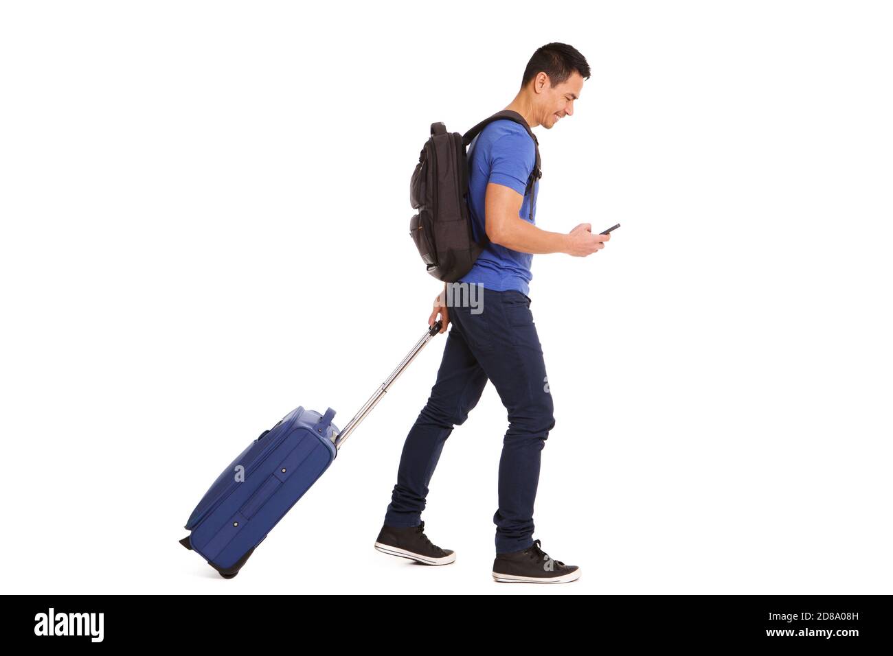 Ritratto a corpo pieno di un uomo maturo sorridente che cammina con valigia e cellulare su sfondo bianco Foto Stock