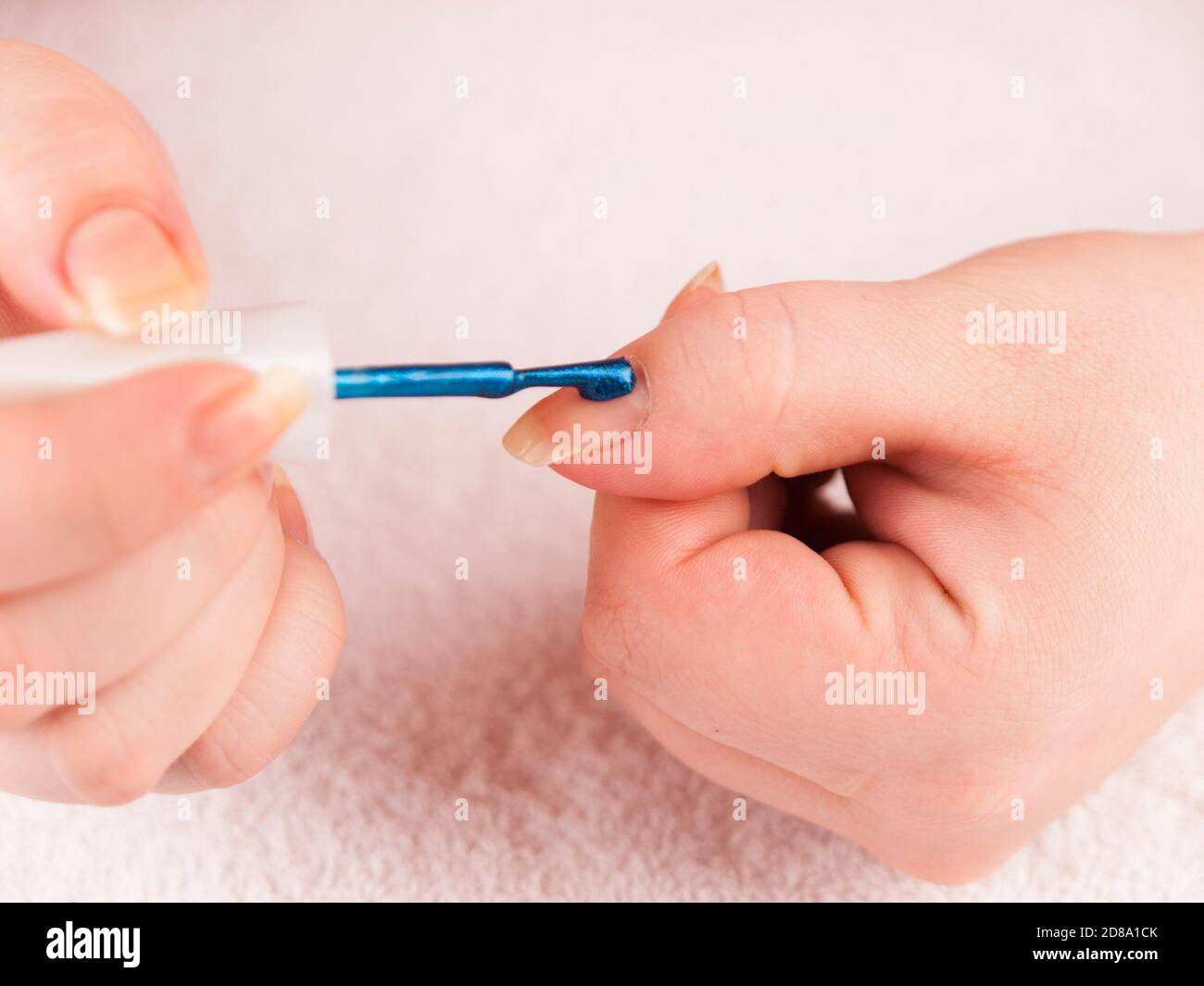 Il concetto di cura delle mani. Il manicurista Closeup applica il gel lucidante per unghie sul dito. Estetista servizio curato con cura. Chiodo. Foto Stock