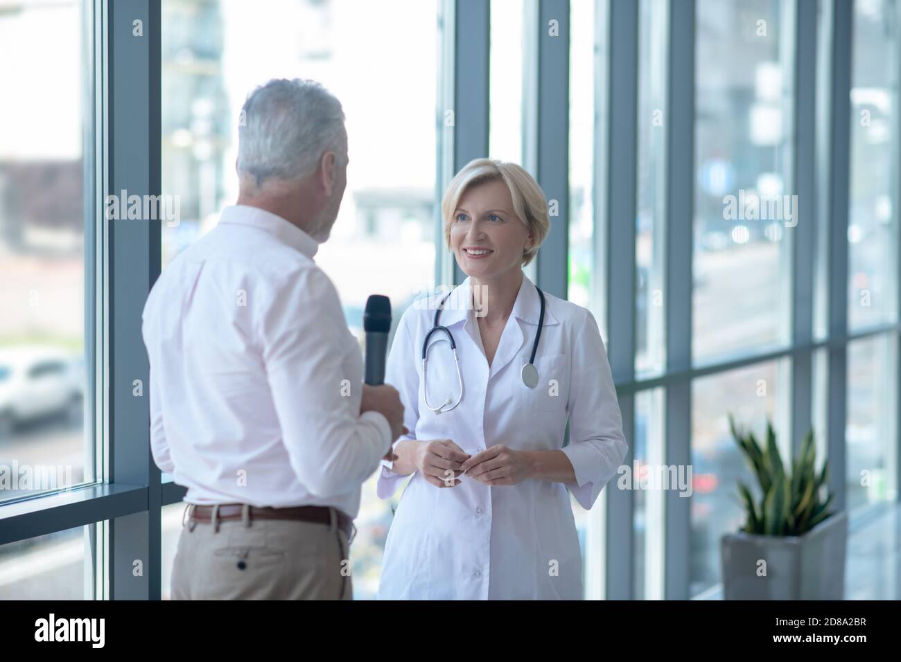 Giornalista di sesso maschile con capelli grigi che intervistano una  dottoressa bionda Foto stock - Alamy