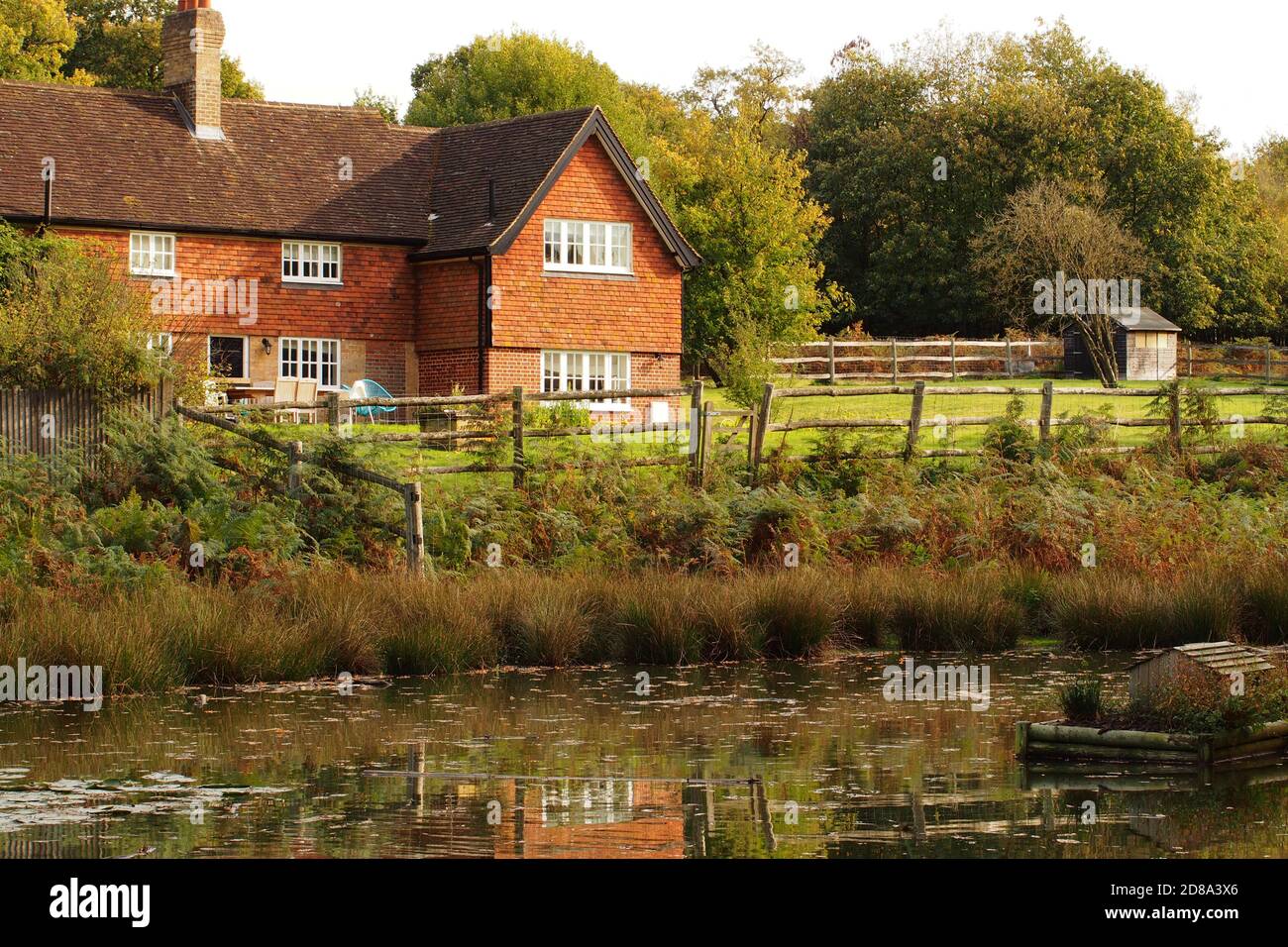 Una vista di Keepers Cottage a Knole Park, Kent, Inghilterra con il laghetto delle anatre e casa galleggiante delle anatre dietro la proprietà in primo piano Foto Stock