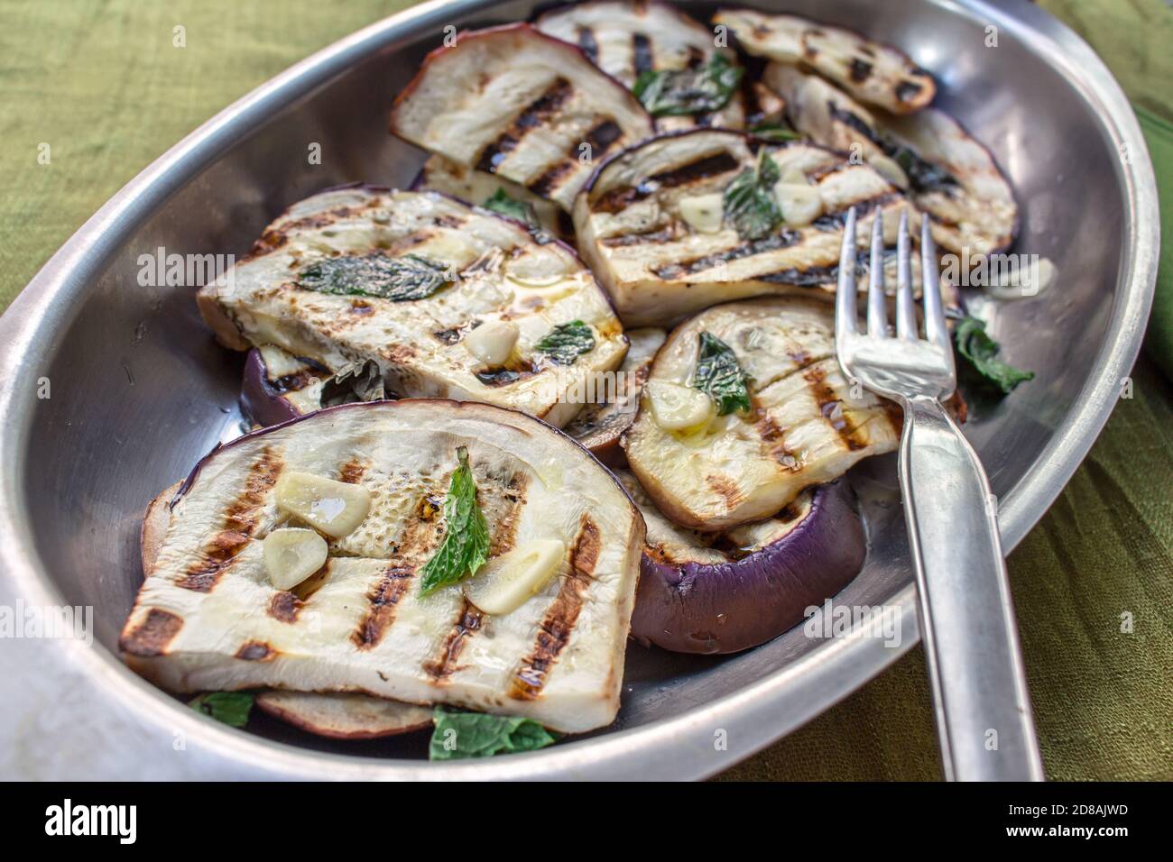 Cucina siciliana: Una teglia in metallo con melanzane tunisine alla griglia e condita con olio d'oliva, aglio e menta fresca Foto Stock
