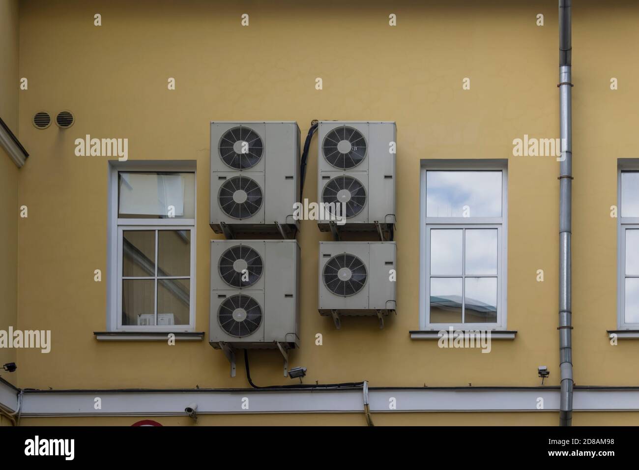 Condizionatori d'aria sulla parete gialla. Primo piano . Un ambiente urbano moderno in uno sviluppo del diciannovesimo secolo. Foto Stock