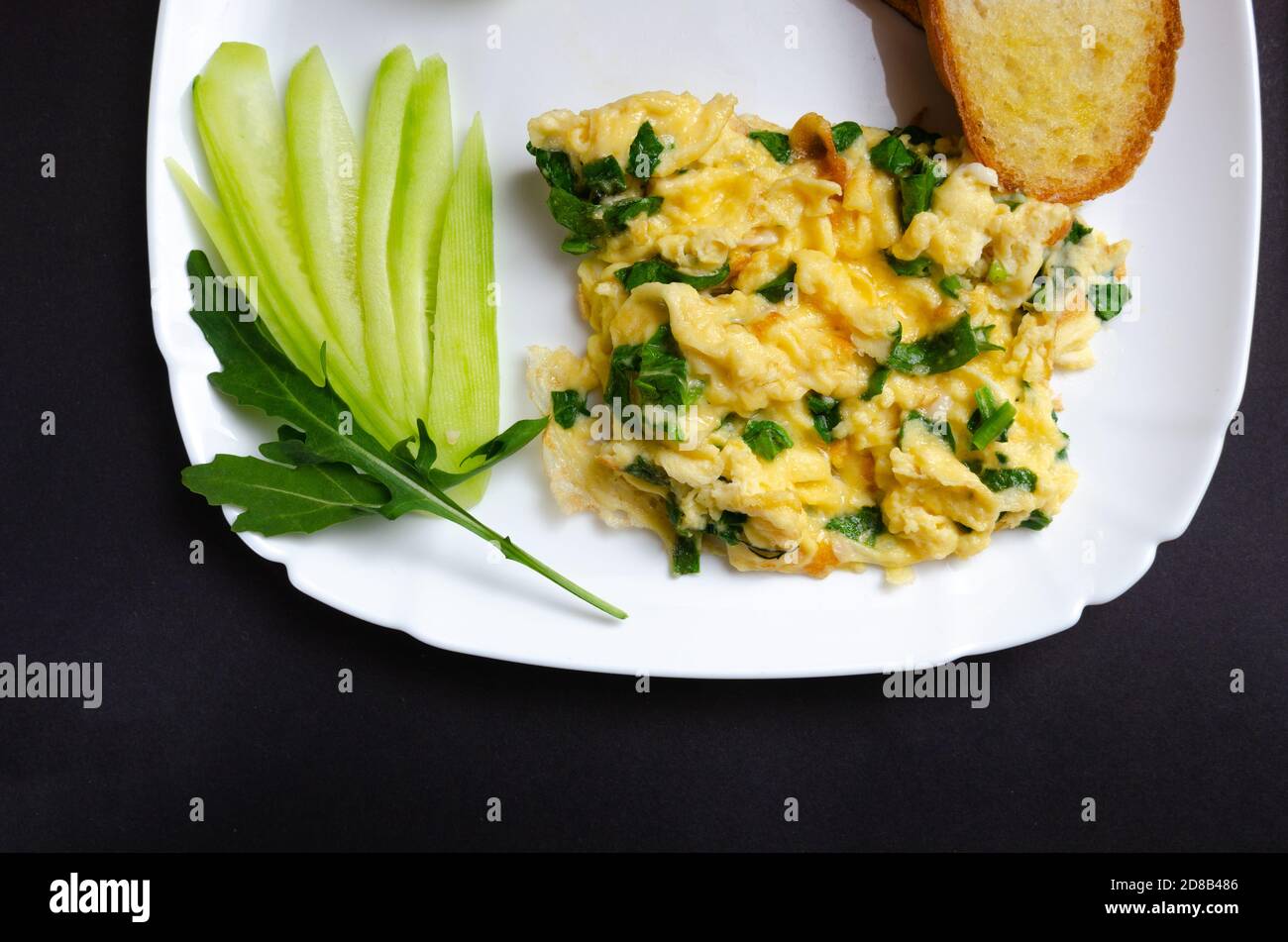 Una bella foto di una frittata con spinaci e crostini su un piatto bianco. Su uno sfondo grigio con spazio libero per il testo. Vista dall'alto Foto Stock