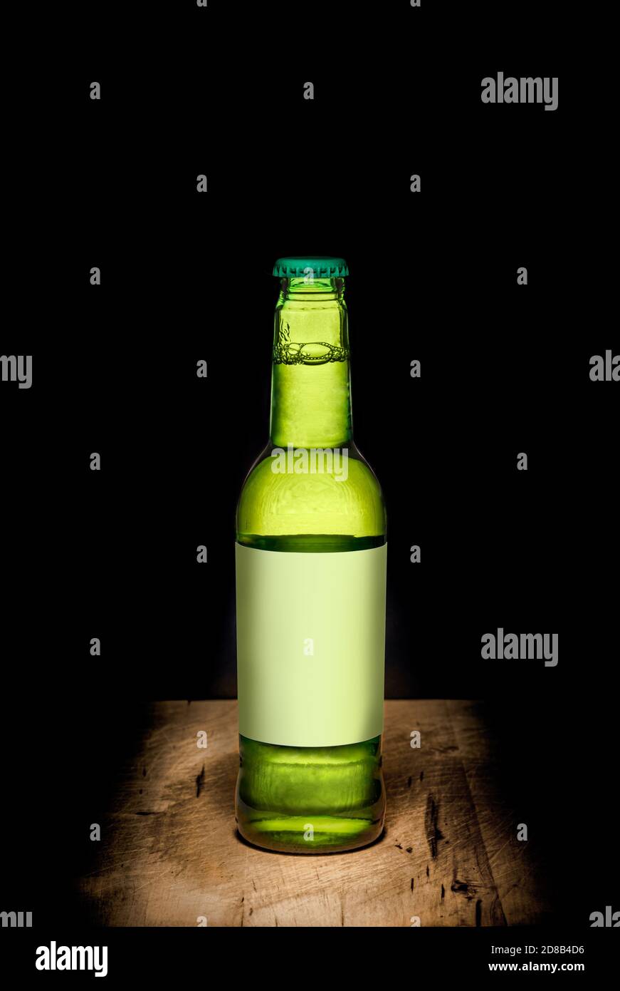 Bottiglia di vetro di birra limone - colore verde su un legno tavolo contro il nero Foto Stock