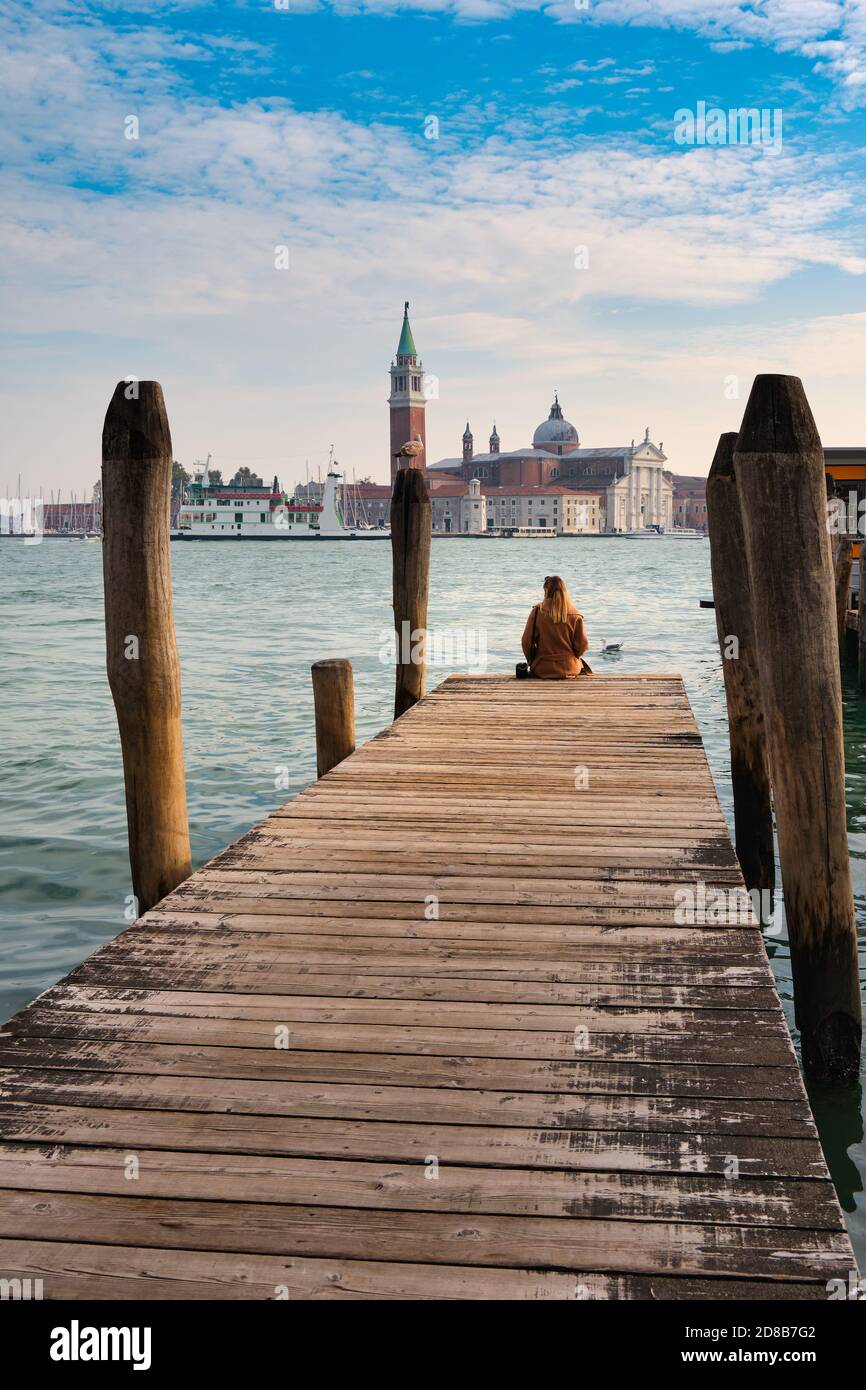 Vacanze a Venezia. Vista posteriore di bella ragazza che gode di vista sulla Laguna di Venezia con l'isola di San Giorgio maggiore e gondole Foto Stock