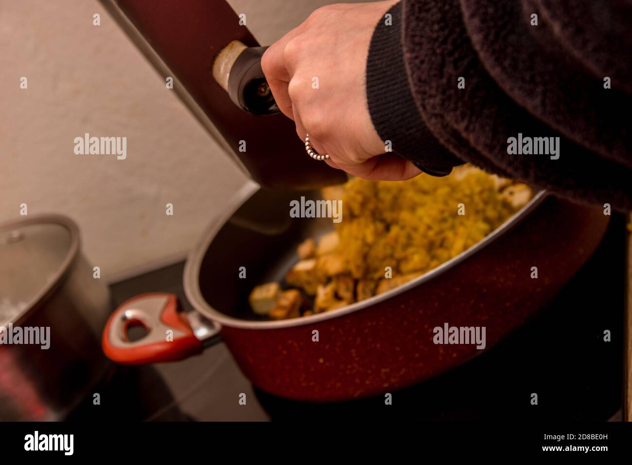 Mano della donna con anello d'argento che mette una certa forma indiana di cibo pan nella pentola Foto Stock