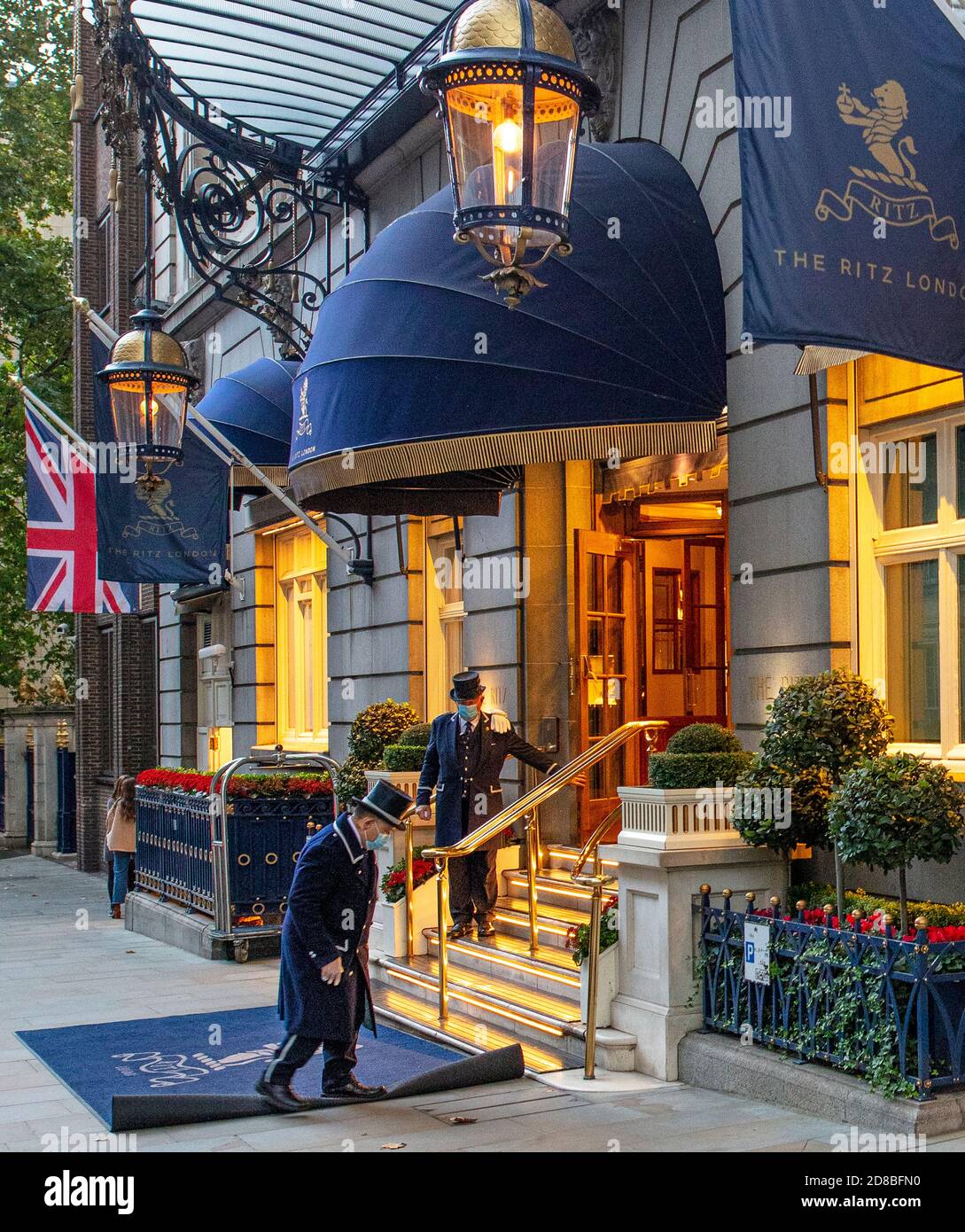 Due portiere fuori dall'ingresso di Arlington St del Ritz Hotel di Londra; indossano maschere contro Covid e aspettano di partecipare agli ospiti. Foto Stock