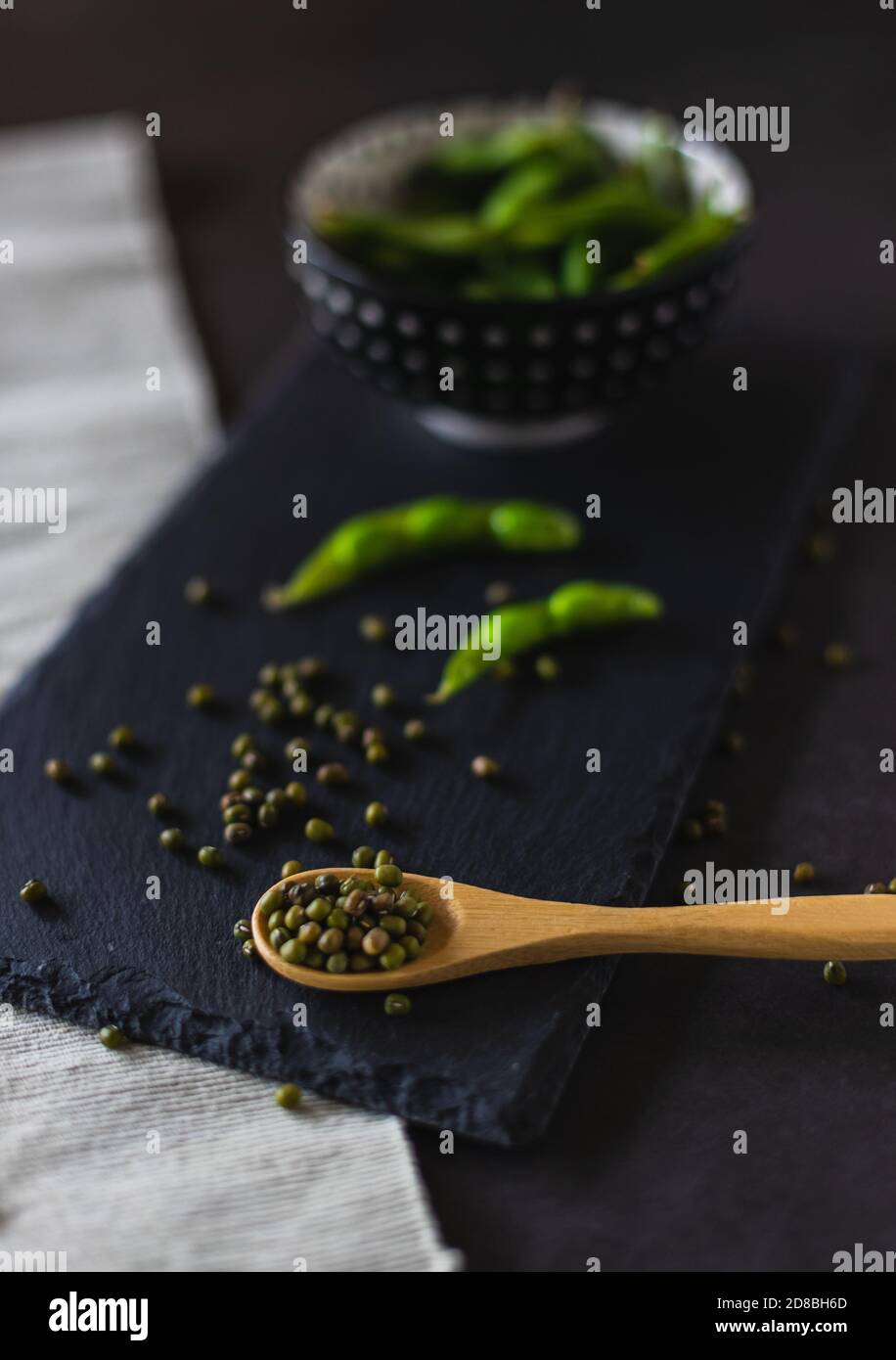 Fagioli di edamame in una ciotola e mungere su un cucchiaio di legno su una tavola di ardesia. Legumi sani con proteine. Foto Stock