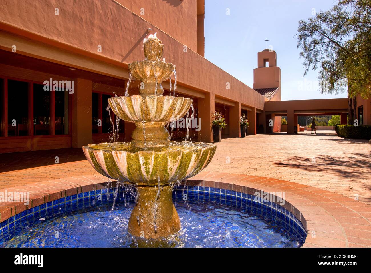 Una fontana fresca bolle nel sole del pomeriggio nel cortile di una chiesa cattolica nel sud della California. Foto Stock
