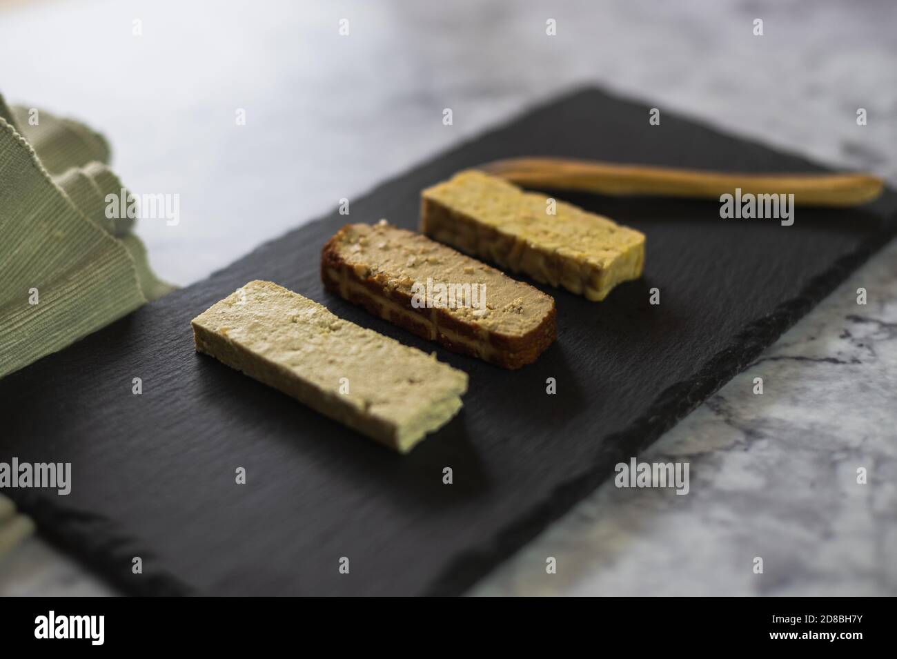 Diversi prodotti di soia su una piastra di ardesia. Tofu solido, tofu affumicato e tempeh Foto Stock