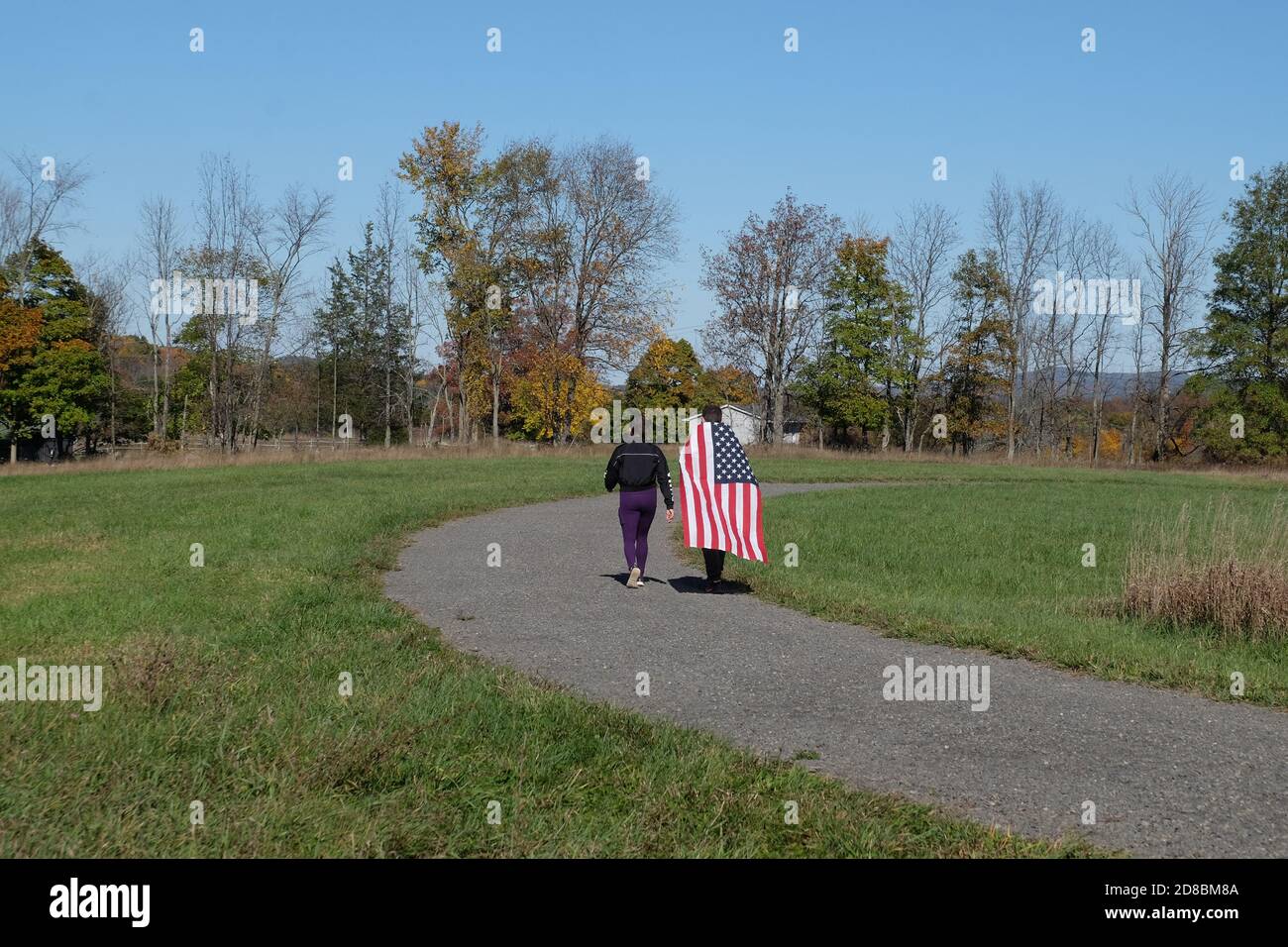 Un uomo cammina drappeggiato in una bandiera americana vicino a New Paltz, NY Foto Stock