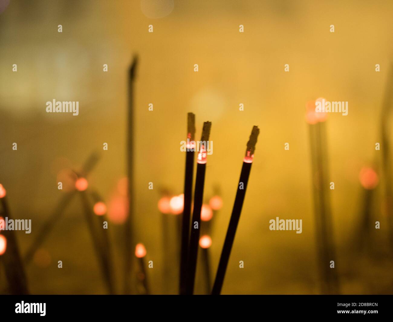 un centinaio di bastoni di incenso si annientano in un tempio dello sri lanka emissione di una luce arancione Foto Stock