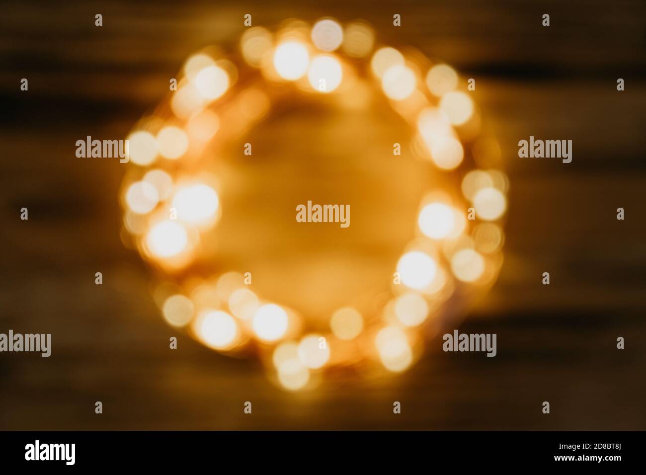 Luci sfocate di Natale a forma di cerchio su sfondo di legno. Sfondo accogliente e creativo festoso. Spazio per il testo. Foto Stock