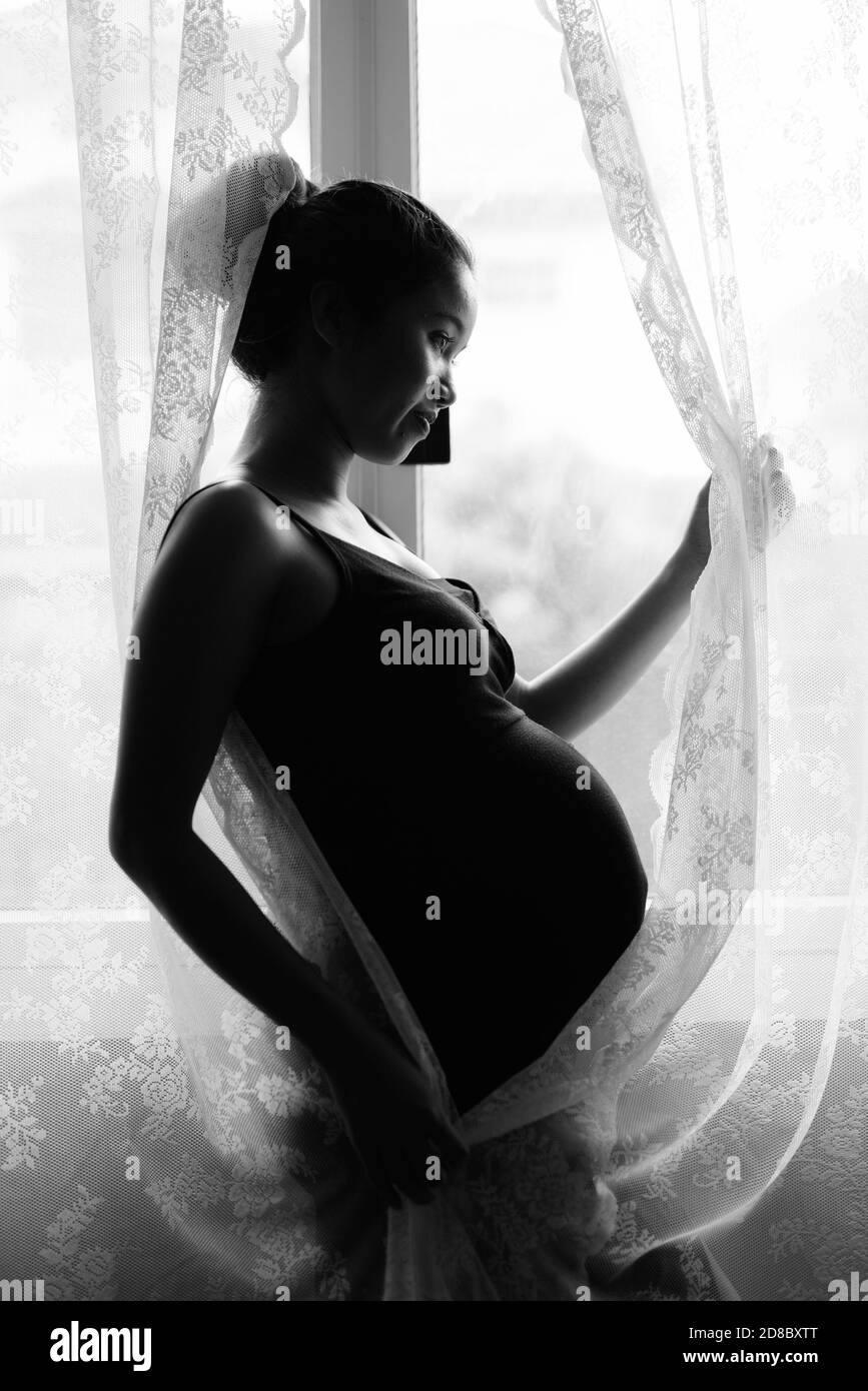 Madre di amare il suo bambino in silhouette mediante la finestra Foto Stock