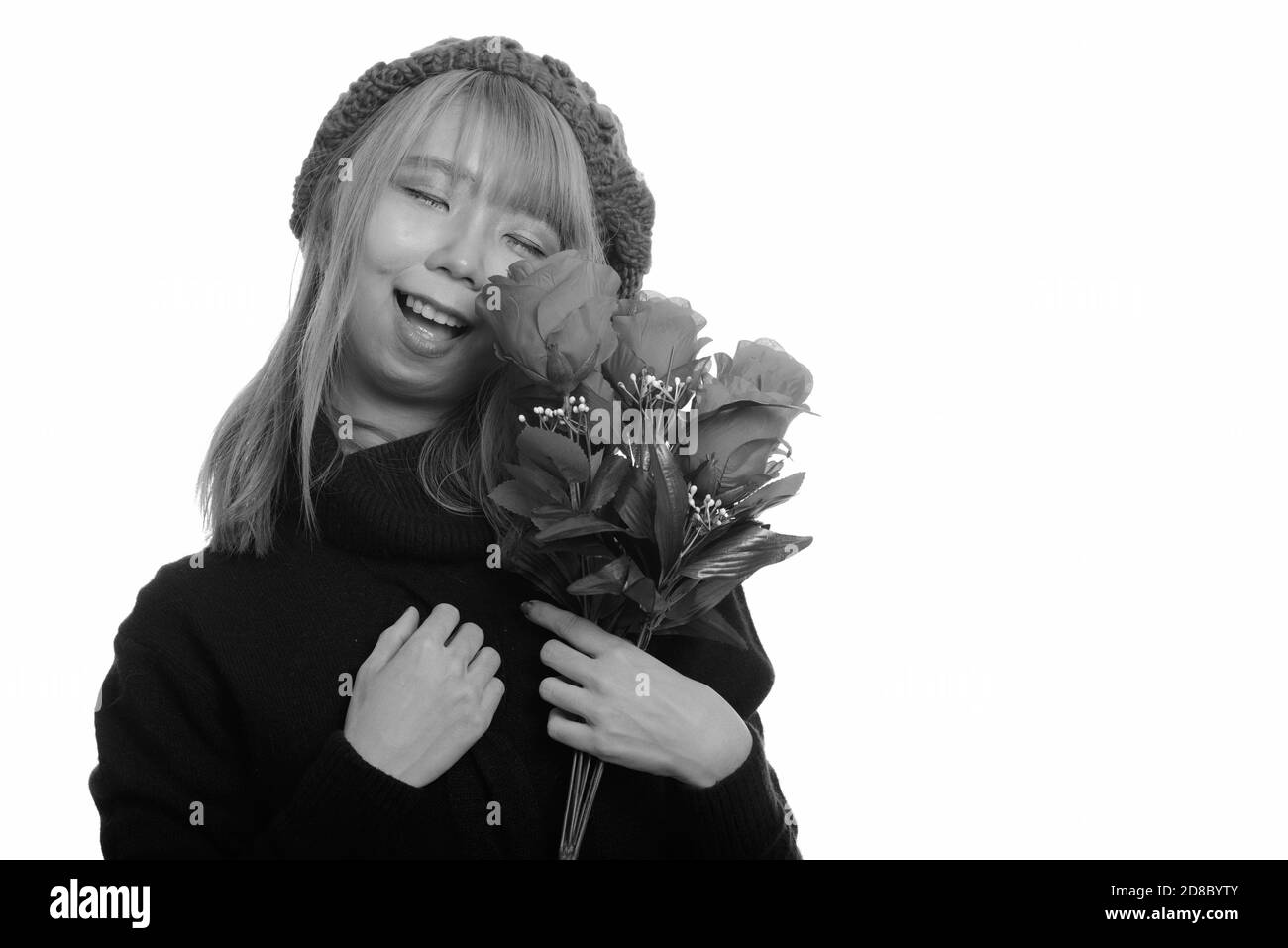 Giovane donna asiatica felice sorridente con gli occhi chiusi tenendo le rose Foto Stock