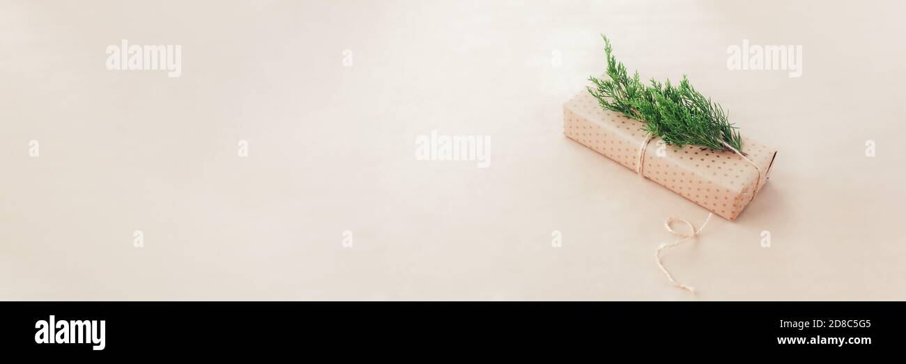 Natale zero rifiuti concetto. Accogliente confezione regalo avvolta in carta artigianale e decorata con ramificazione di cipresso verde. Banner lungo con spazio per la copia Foto Stock
