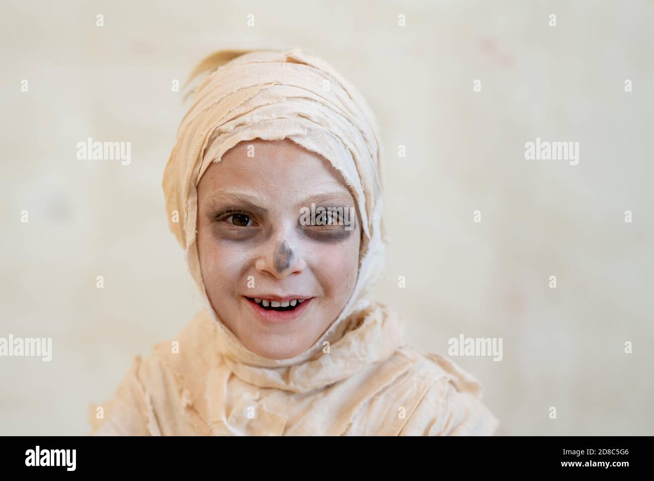 Ritratto di felice ragazzo spensierato coperto di bendaggi come mummia ridendo su sfondo isolato, concetto di Halloween Foto Stock