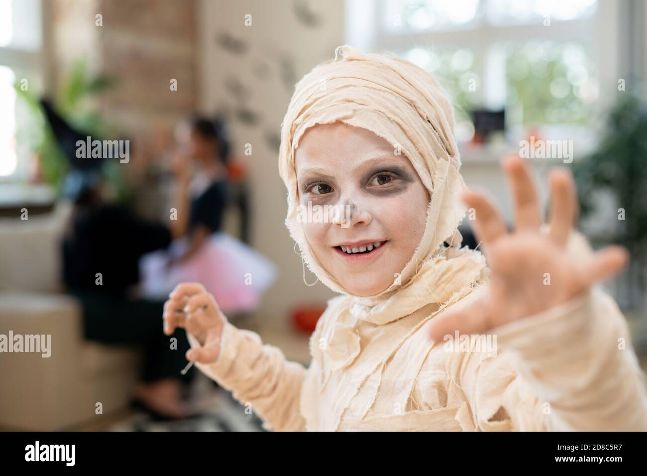 Ritratto di allegro mummia ragazzo coperto di bendaggi gesturanti mani Mentre ti spaventa su Halloween Foto Stock