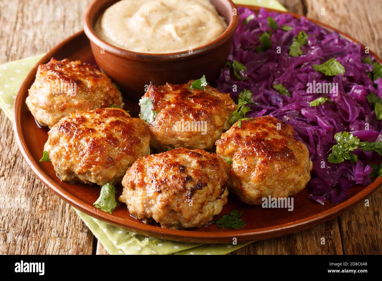 Le polpette di Frikadeller o Danish sono polpette salate servite con salsa cremosa e stufate il cavolo rosso da vicino nel piatto sul tavolo. Orizzontale Foto Stock