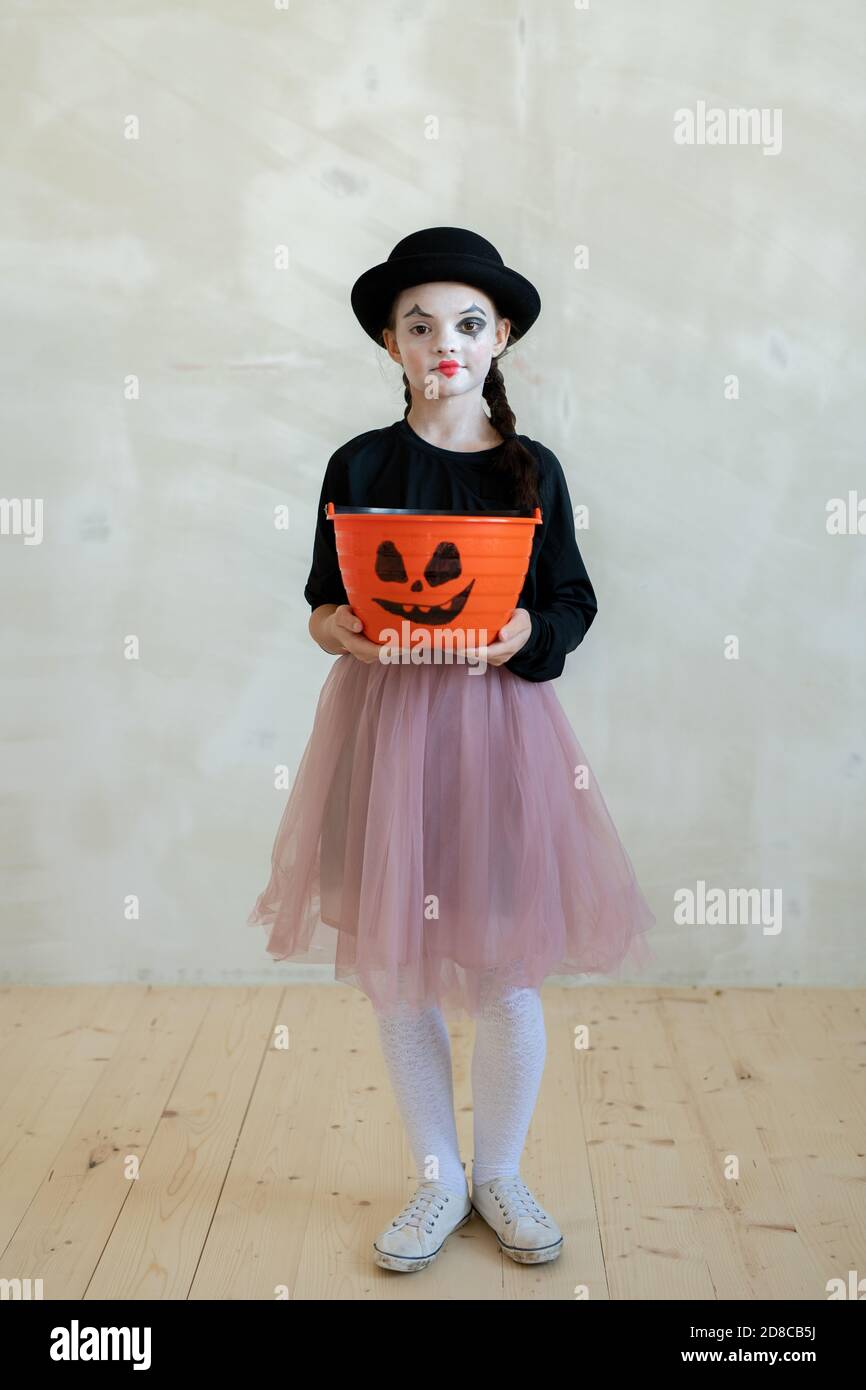 Ritratto di soddisfare intrecciato ragazza in gonna di tut che tiene arancione Secchio per i dolci di Halloween contro il muro Foto Stock
