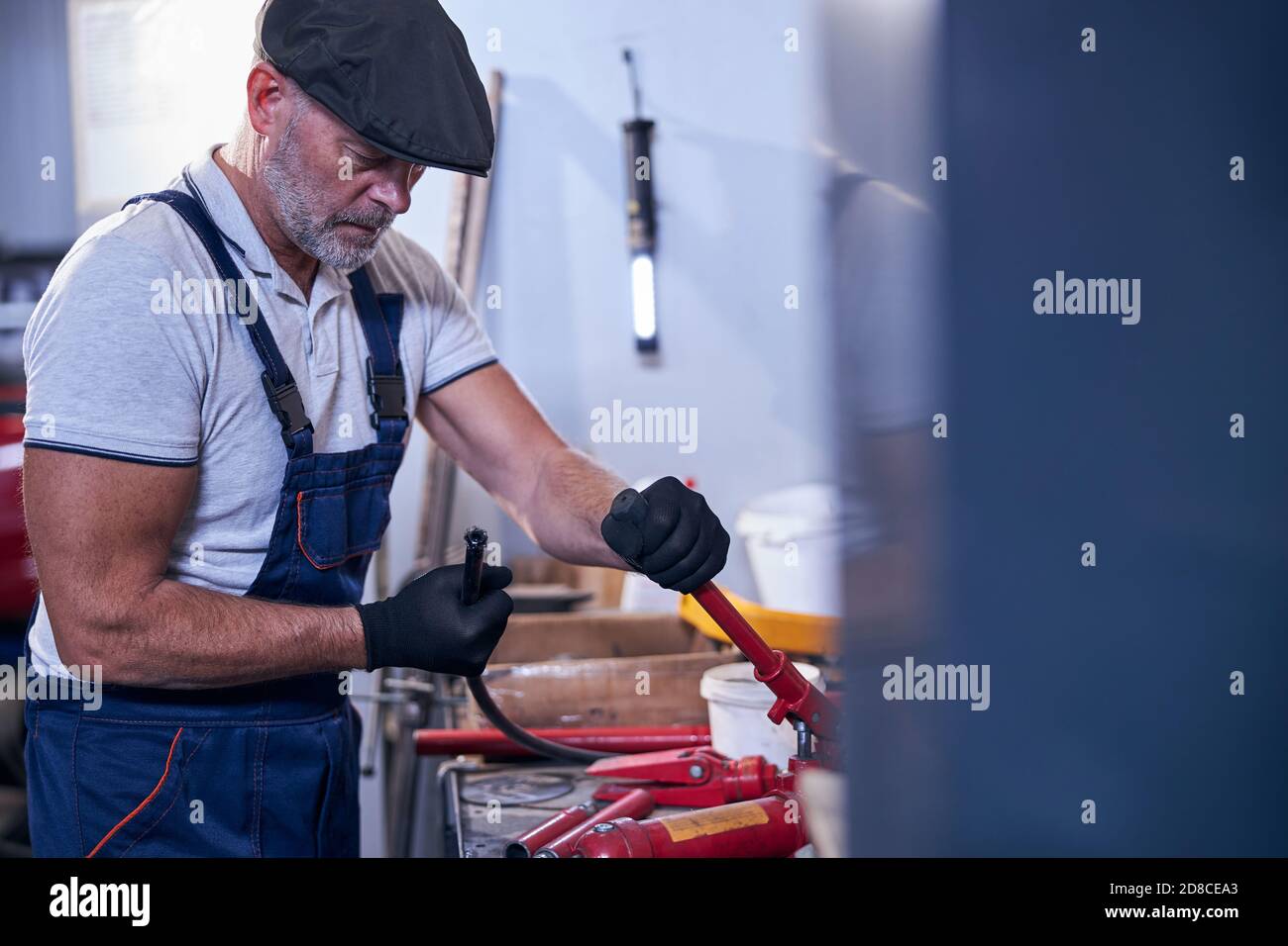 Meccanico maschile con bearded in berretto che lavora in garage Foto Stock