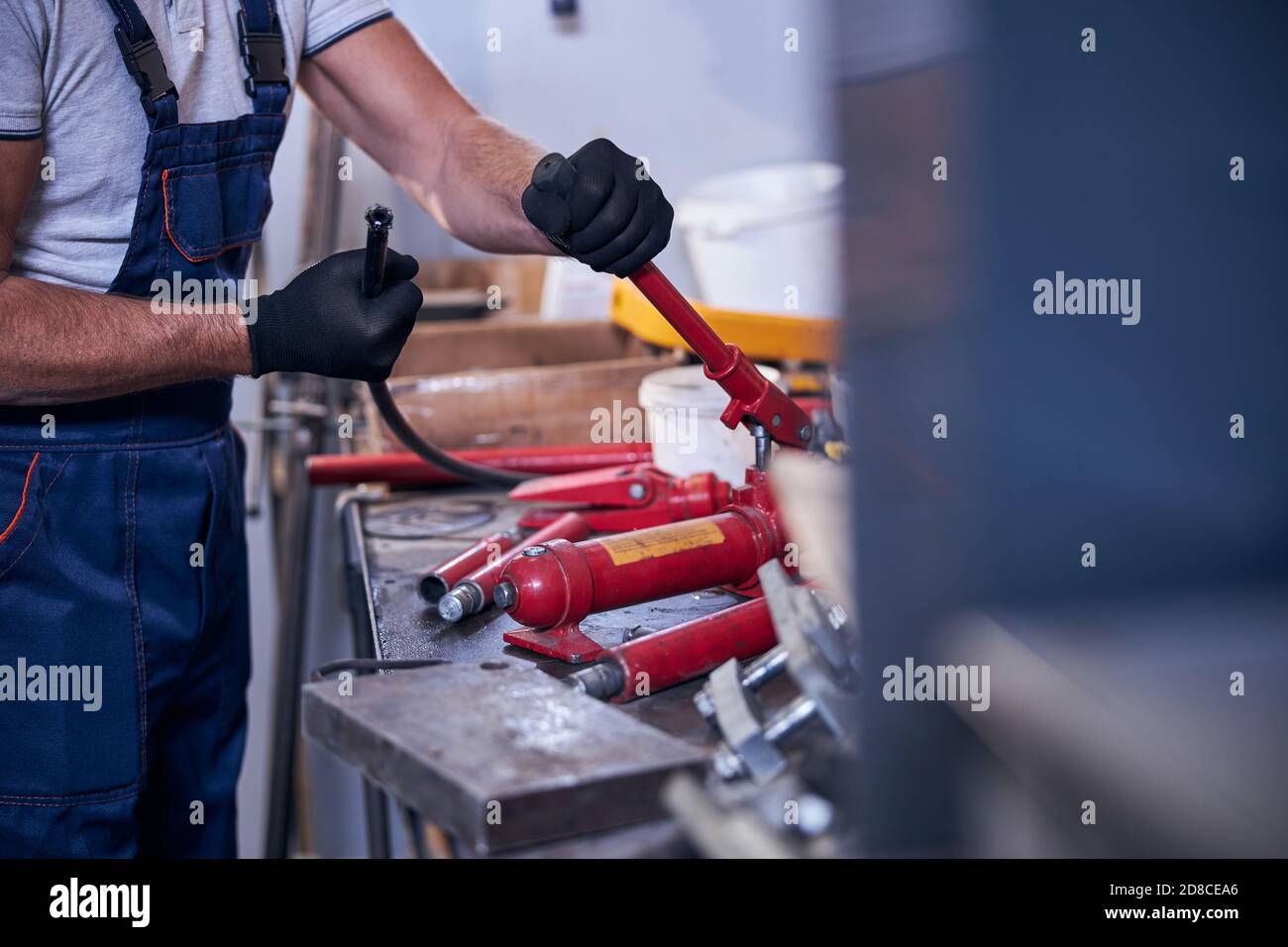 Uomo che assembla l'attrezzo di riparazione di automobile idraulico portatile in garage Foto Stock